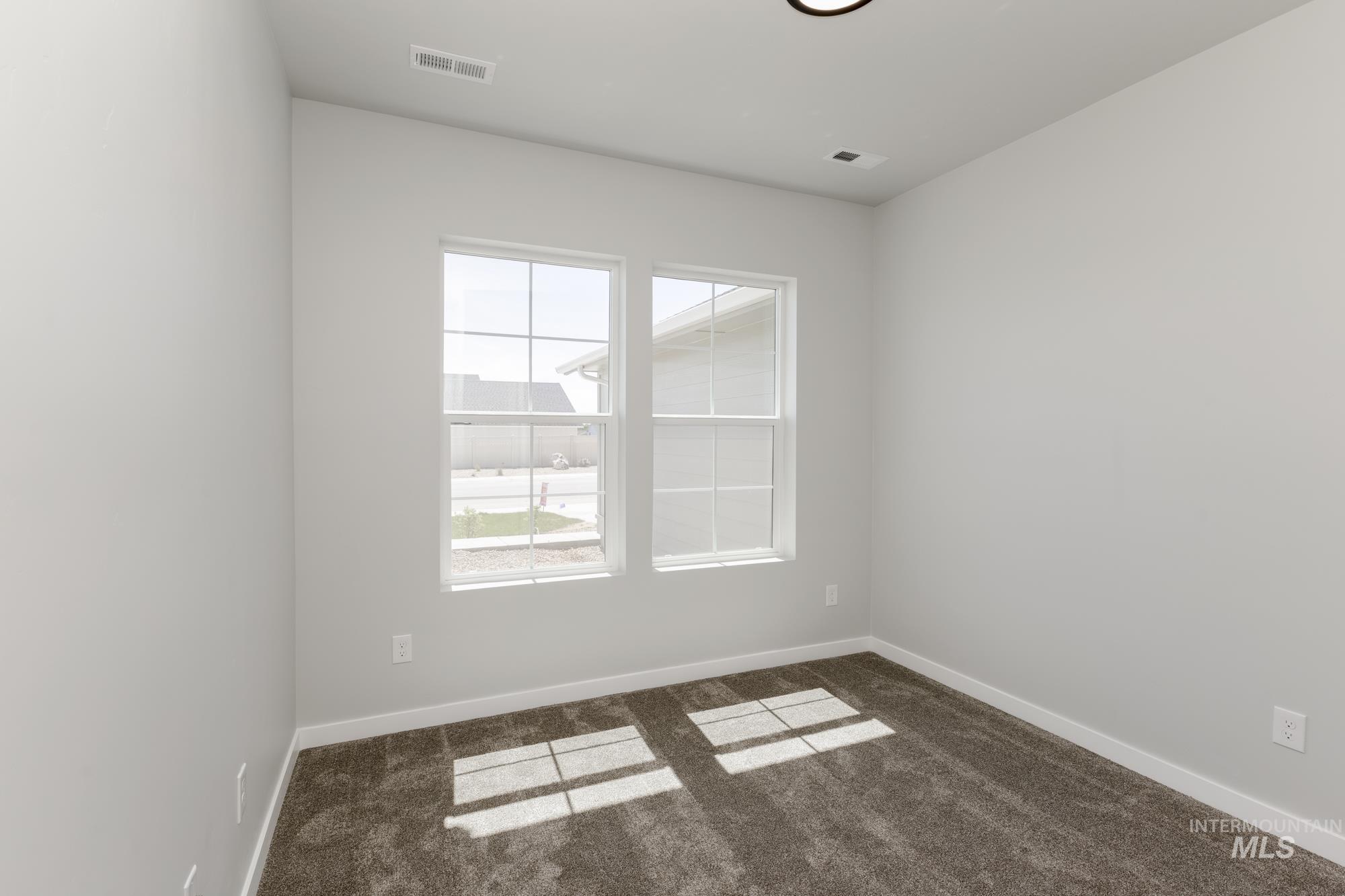 Empty room featuring dark carpet and baseboards