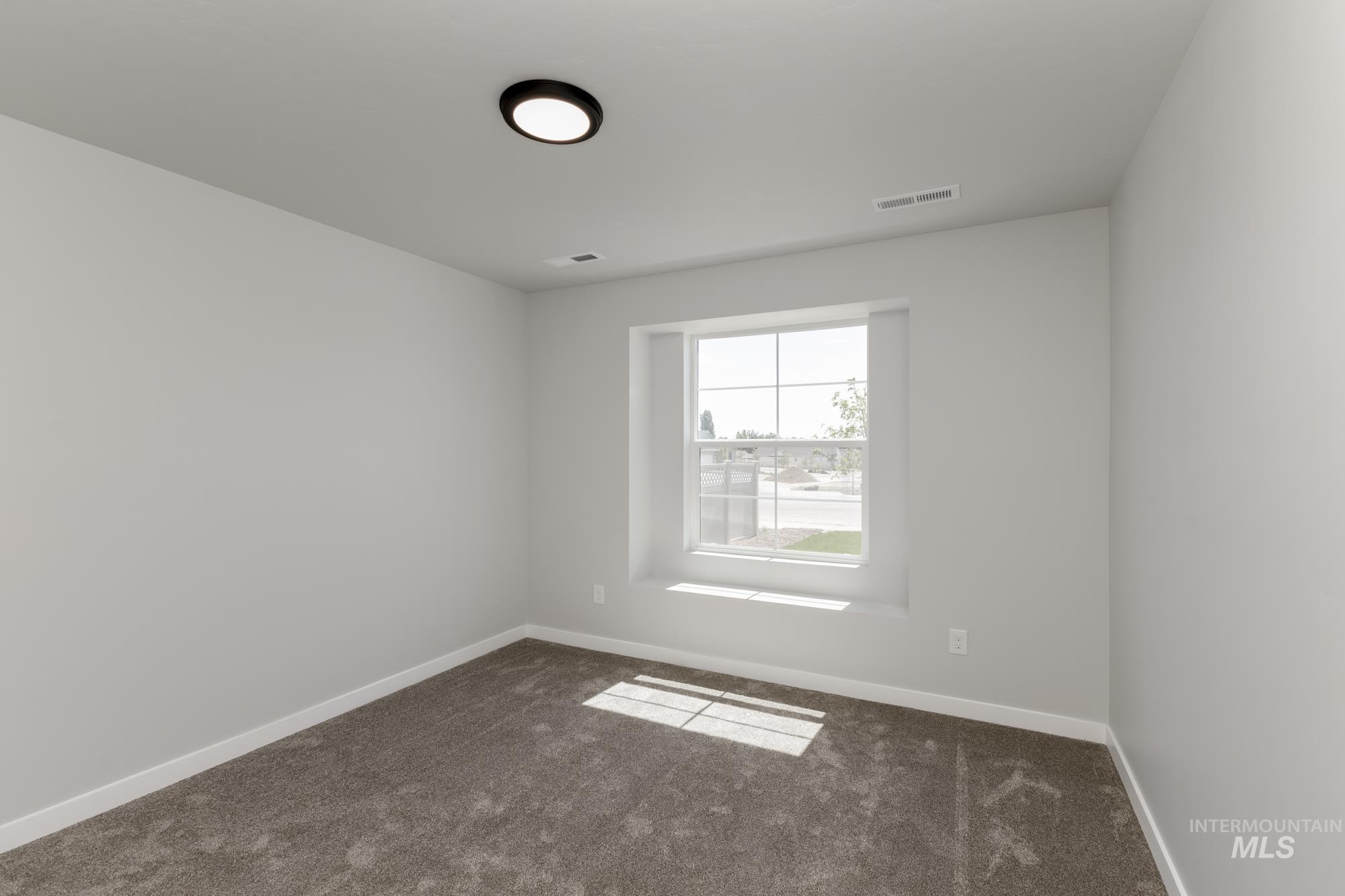 Unfurnished room featuring dark colored carpet and baseboards