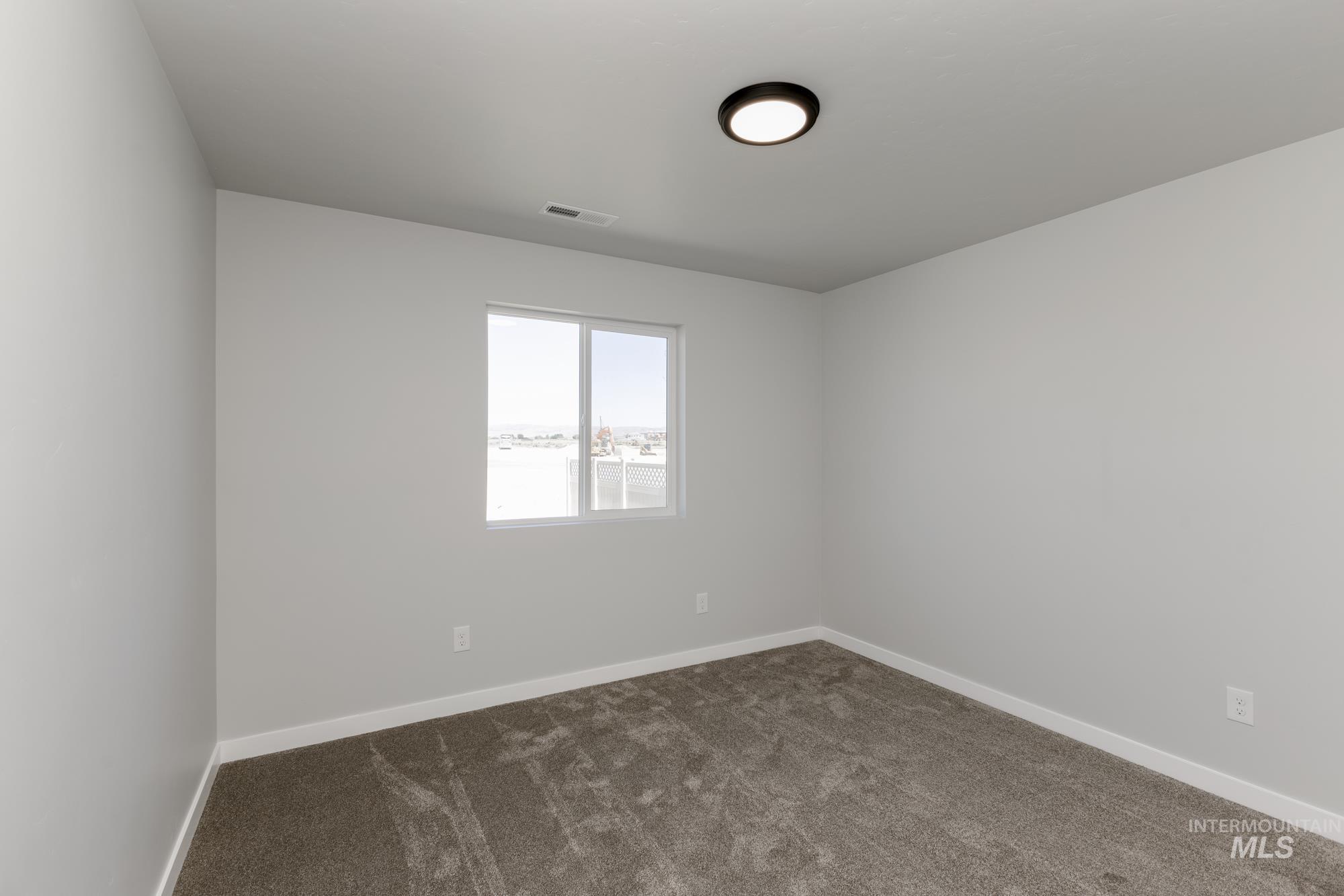 Spare room featuring dark colored carpet and baseboards