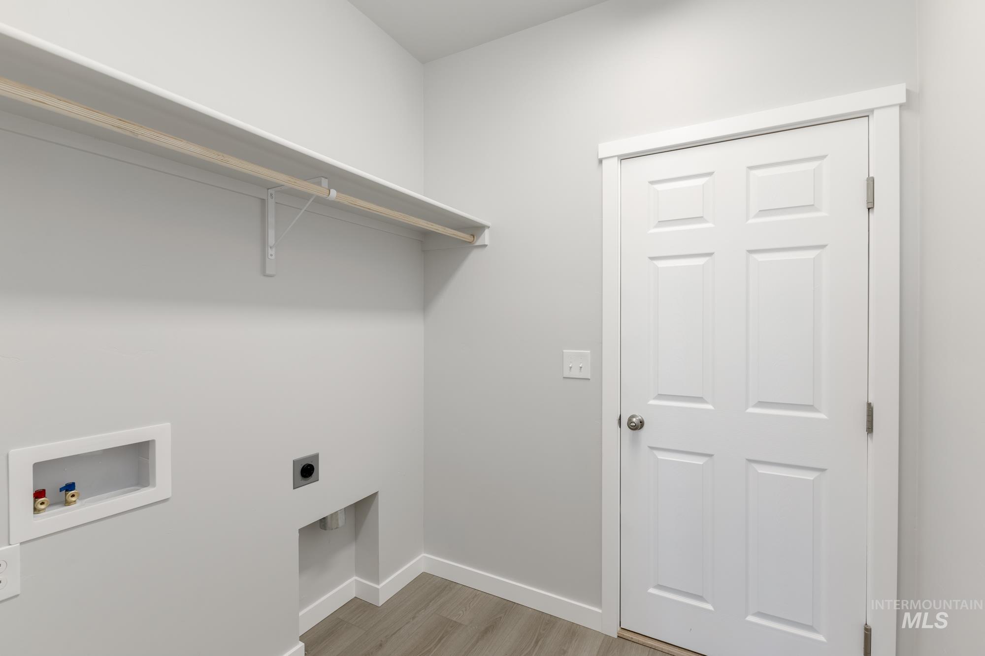 Laundry area featuring light wood-type flooring, hookup for a washing machine, and electric dryer hookup