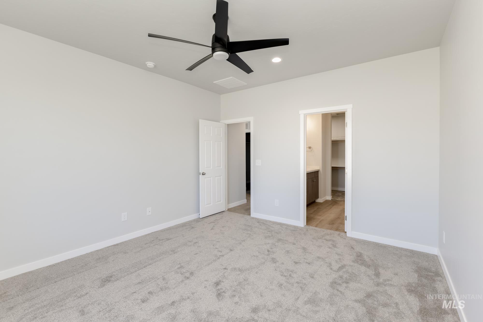 Unfurnished bedroom with light colored carpet, ceiling fan, ensuite bathroom, and recessed lighting
