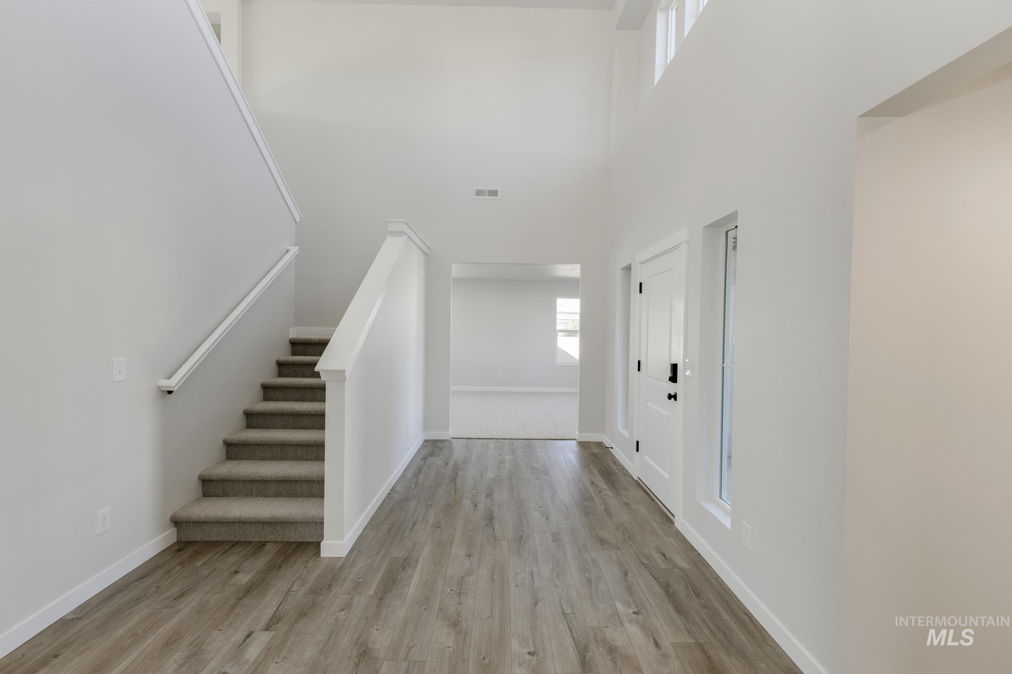 Foyer entrance featuring stairway, light wood finished floors, and a towering ceiling