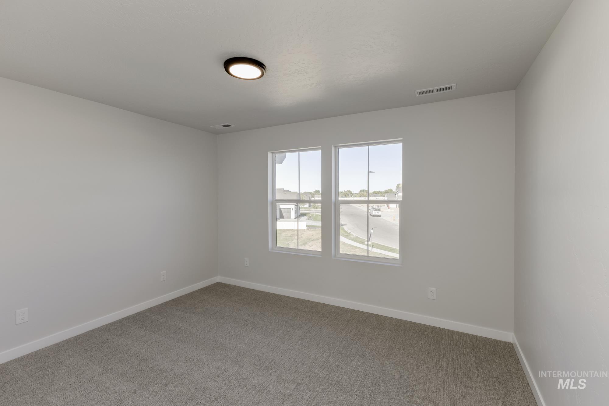 Carpeted spare room featuring baseboards