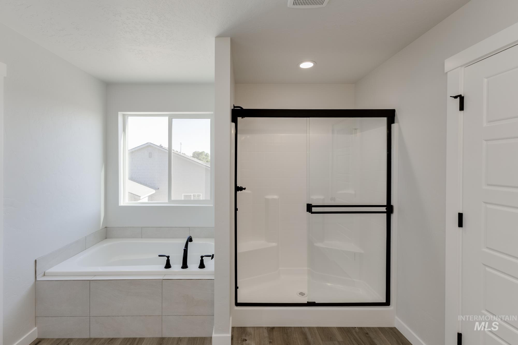 Bathroom featuring a bath, light wood-style floors, a stall shower, and recessed lighting