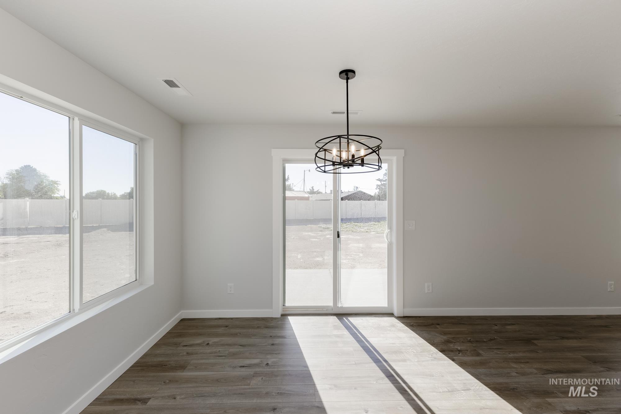 Unfurnished dining area with dark wood-style flooring and a chandelier