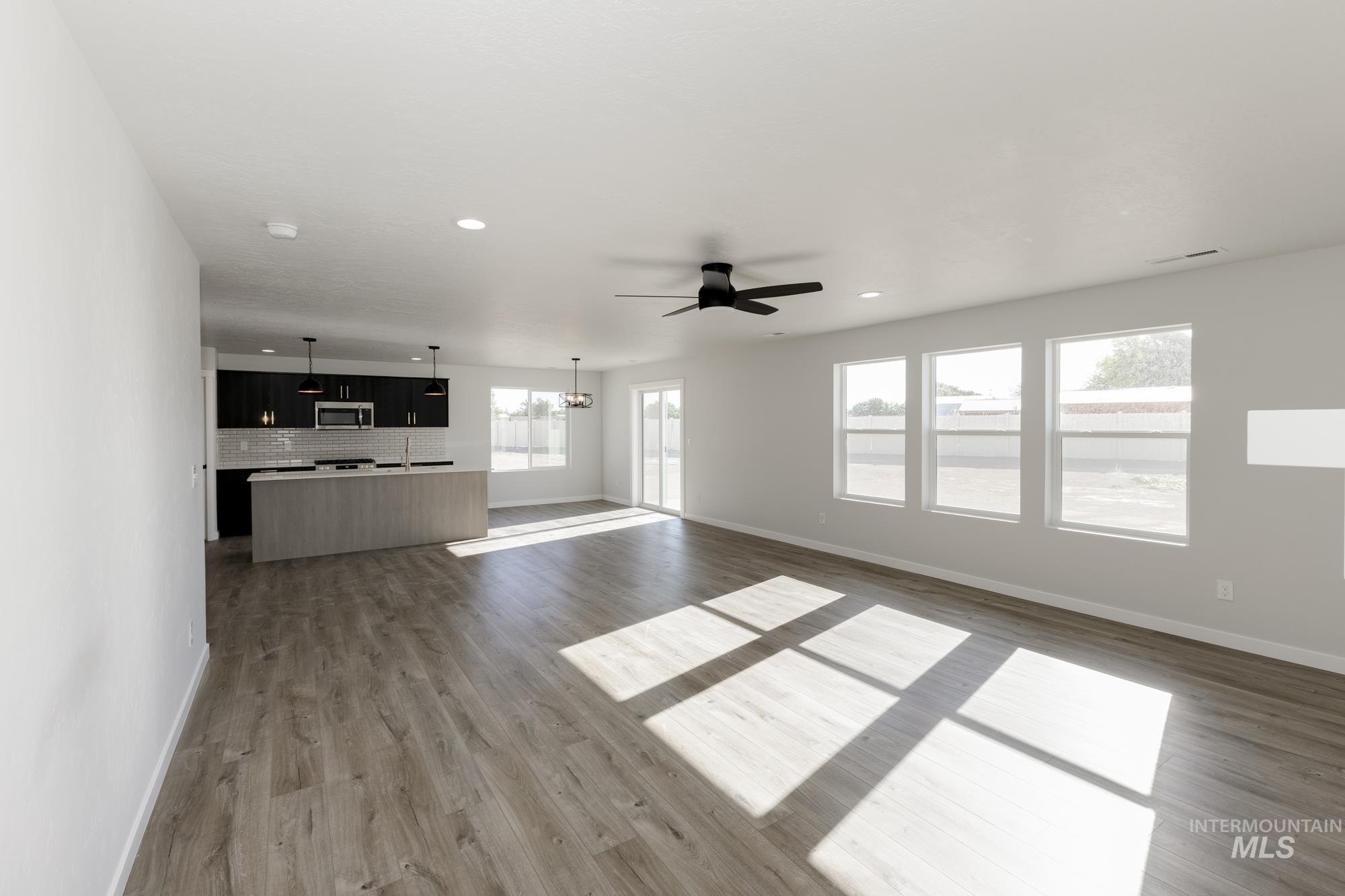 Unfurnished living room with light wood finished floors, a ceiling fan, a chandelier, and recessed lighting