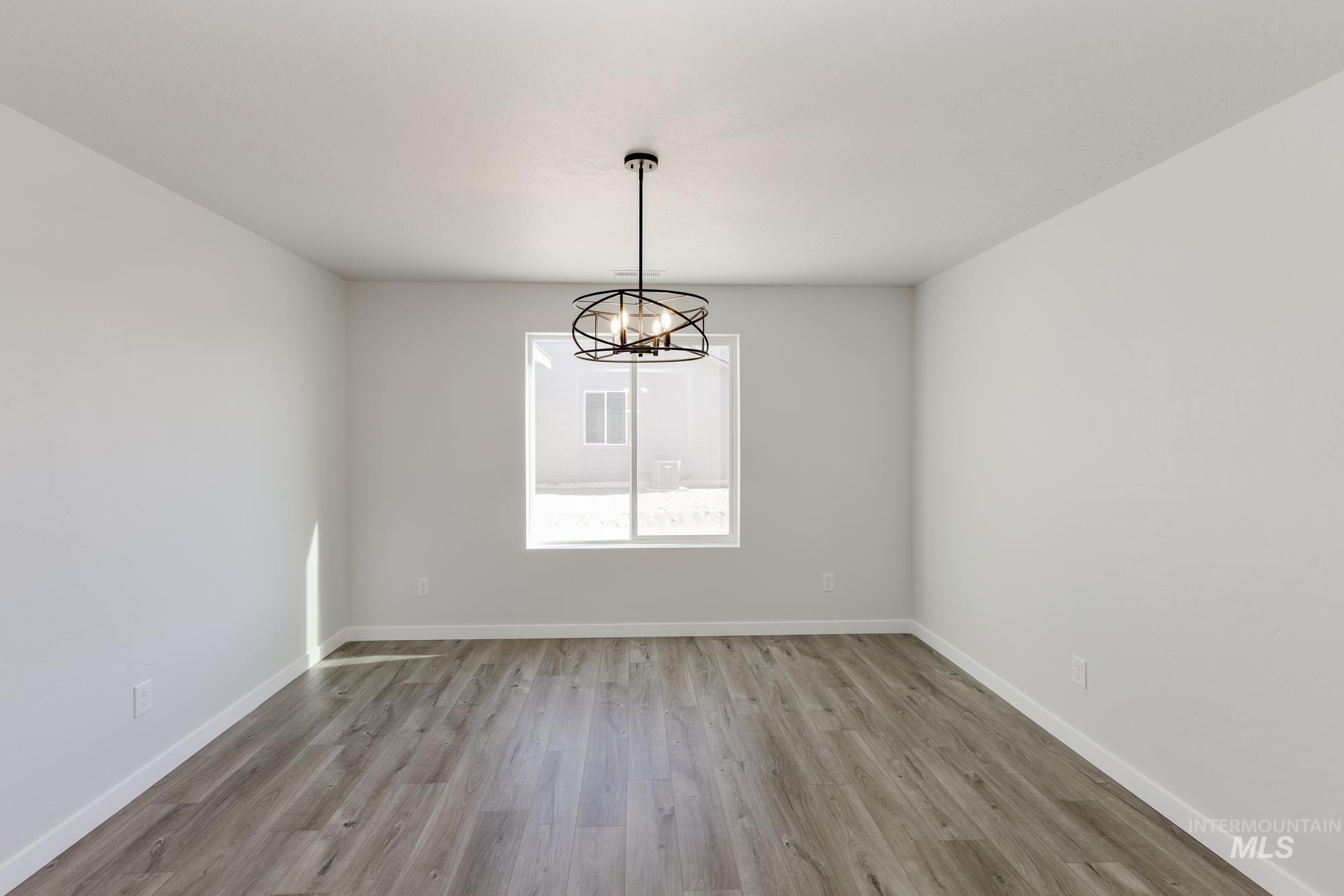Spare room featuring light wood-type flooring and a chandelier