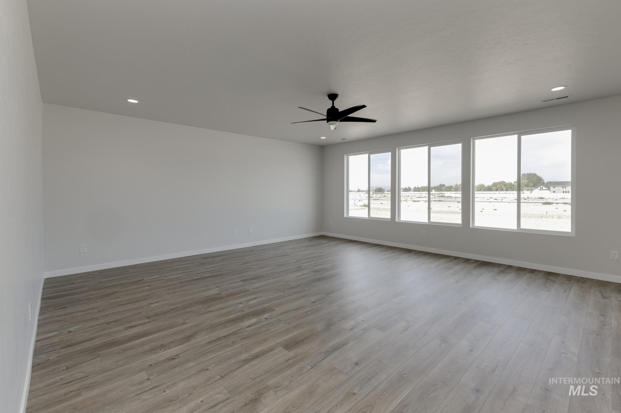 Spare room featuring light wood finished floors, a ceiling fan, and recessed lighting