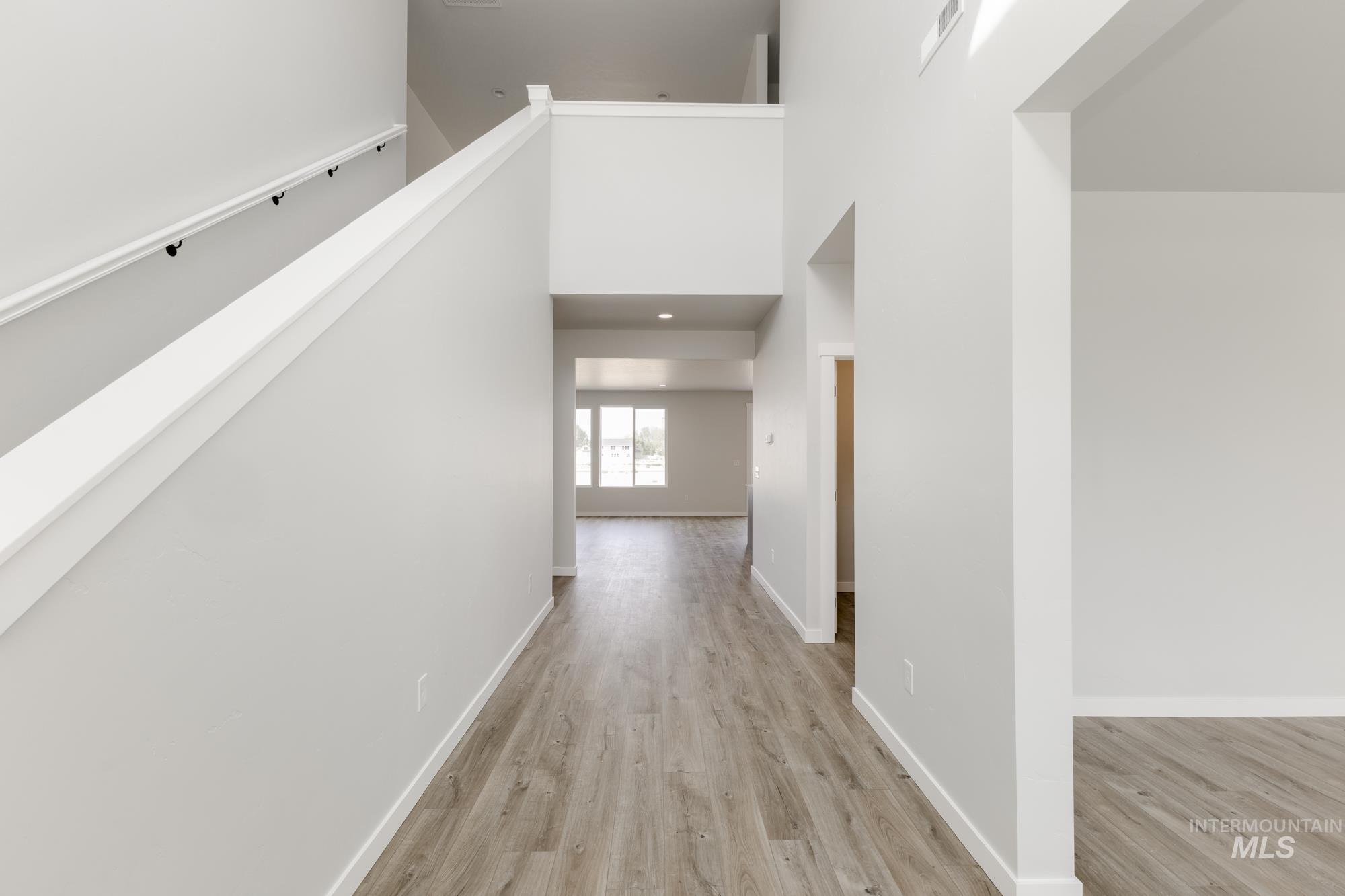 Corridor featuring a towering ceiling and light wood-style flooring