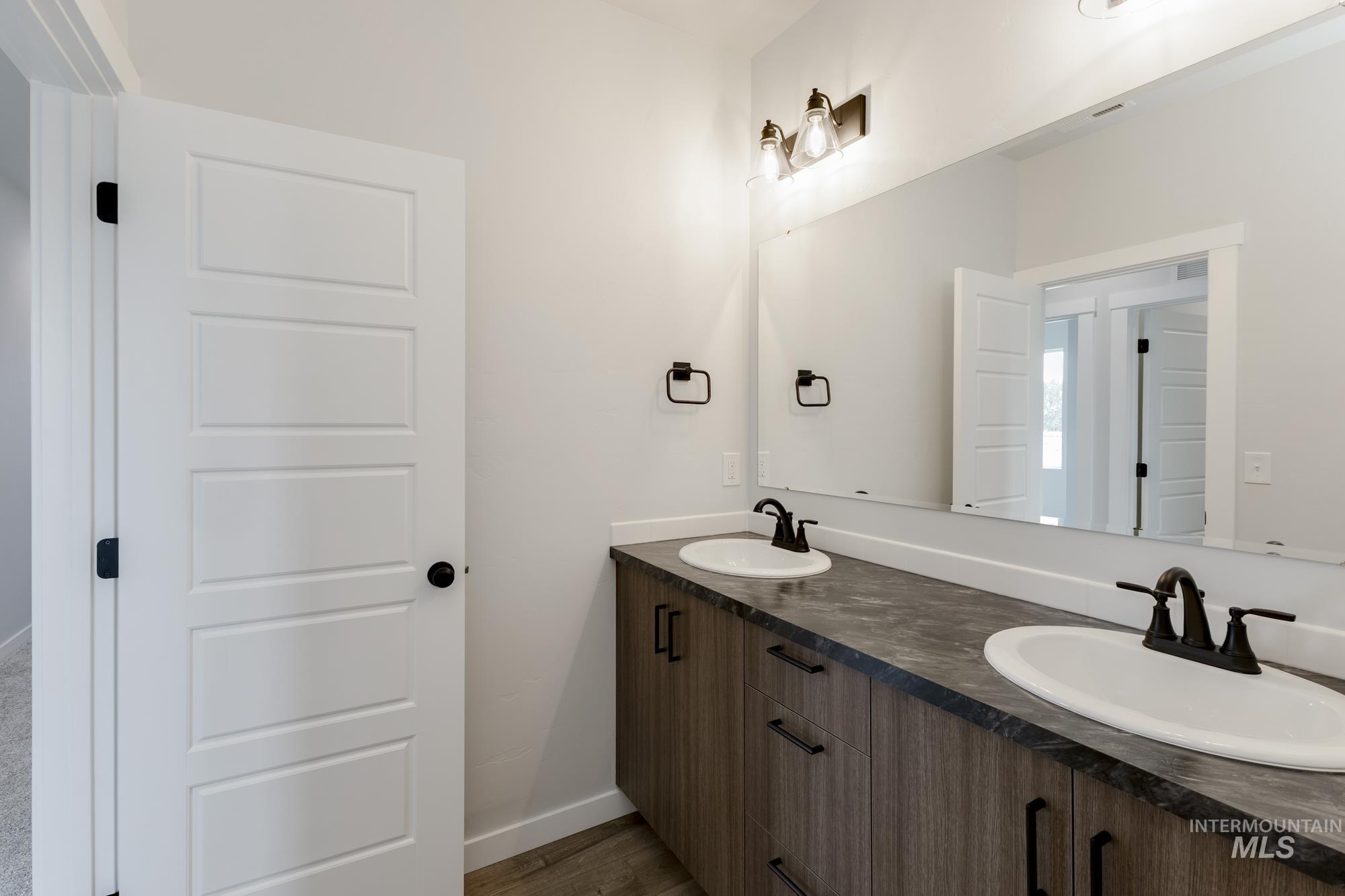Full bath featuring double vanity and wood finished floors