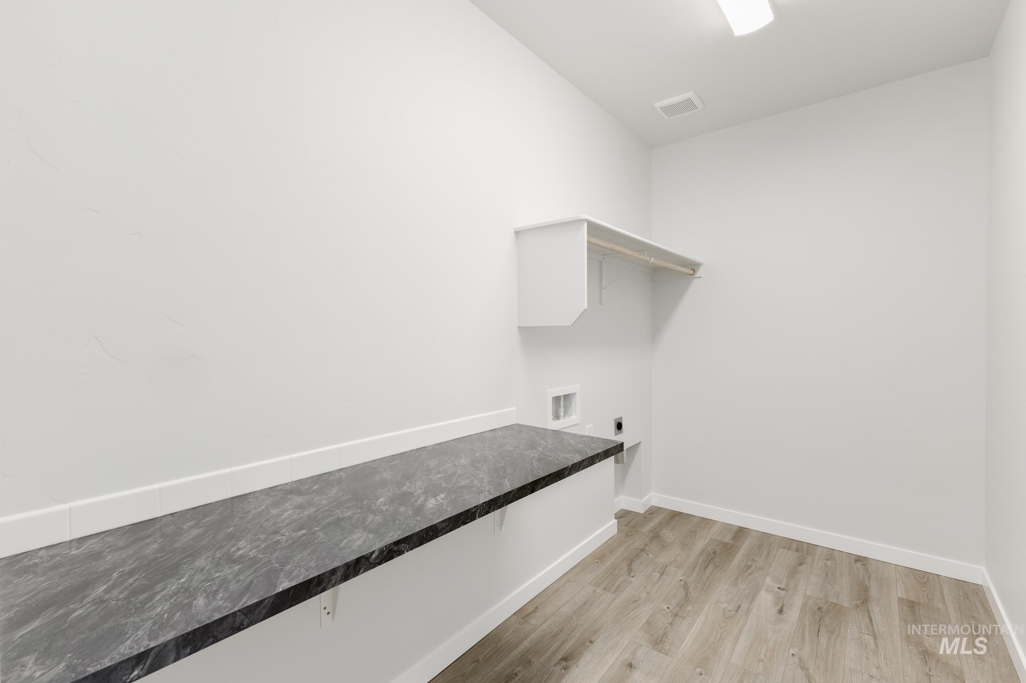Laundry area featuring light wood finished floors and hookup for an electric dryer
