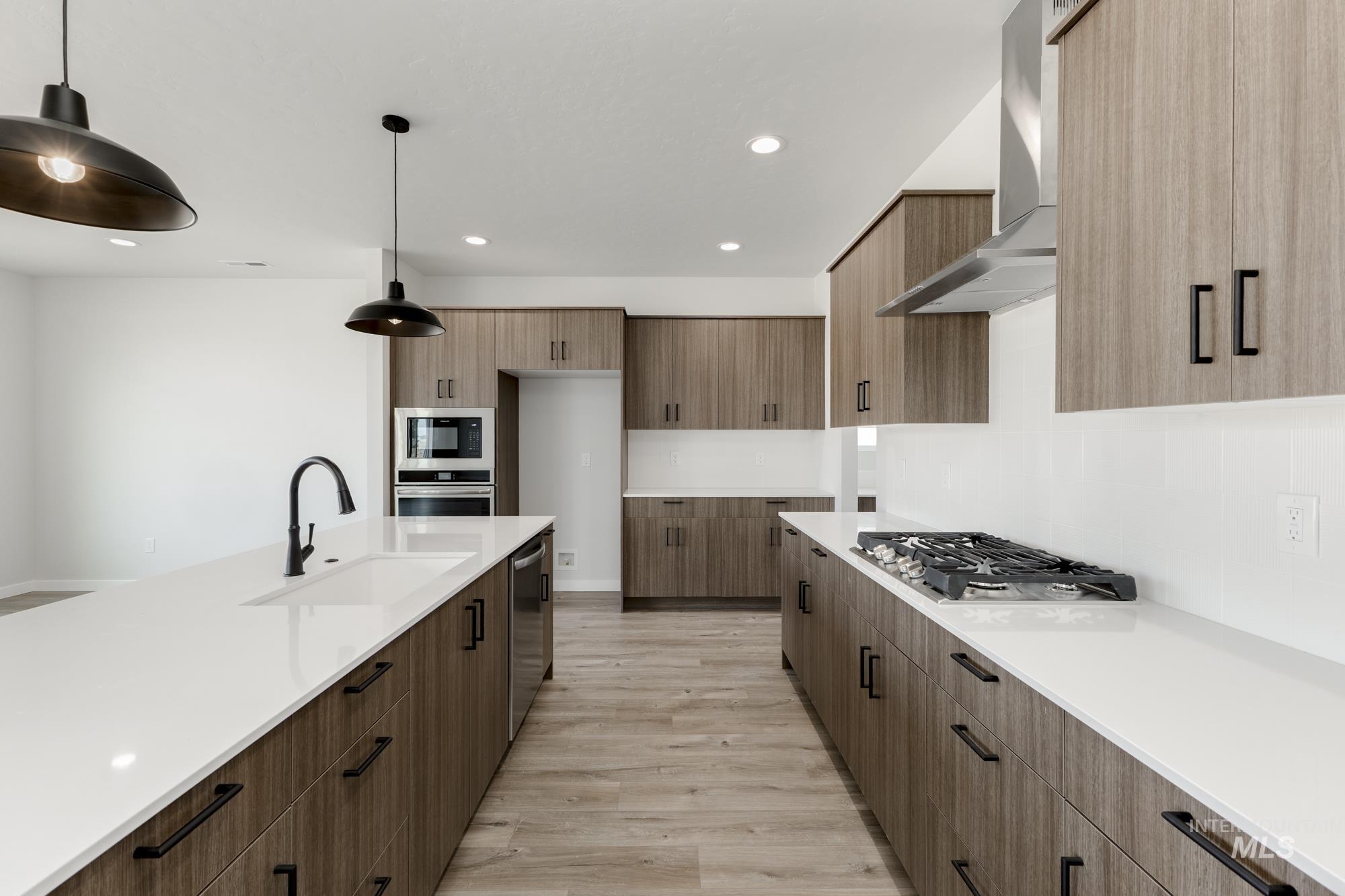 Kitchen with wall chimney range hood, modern cabinets, light wood finished floors, appliances with stainless steel finishes, and recessed lighting