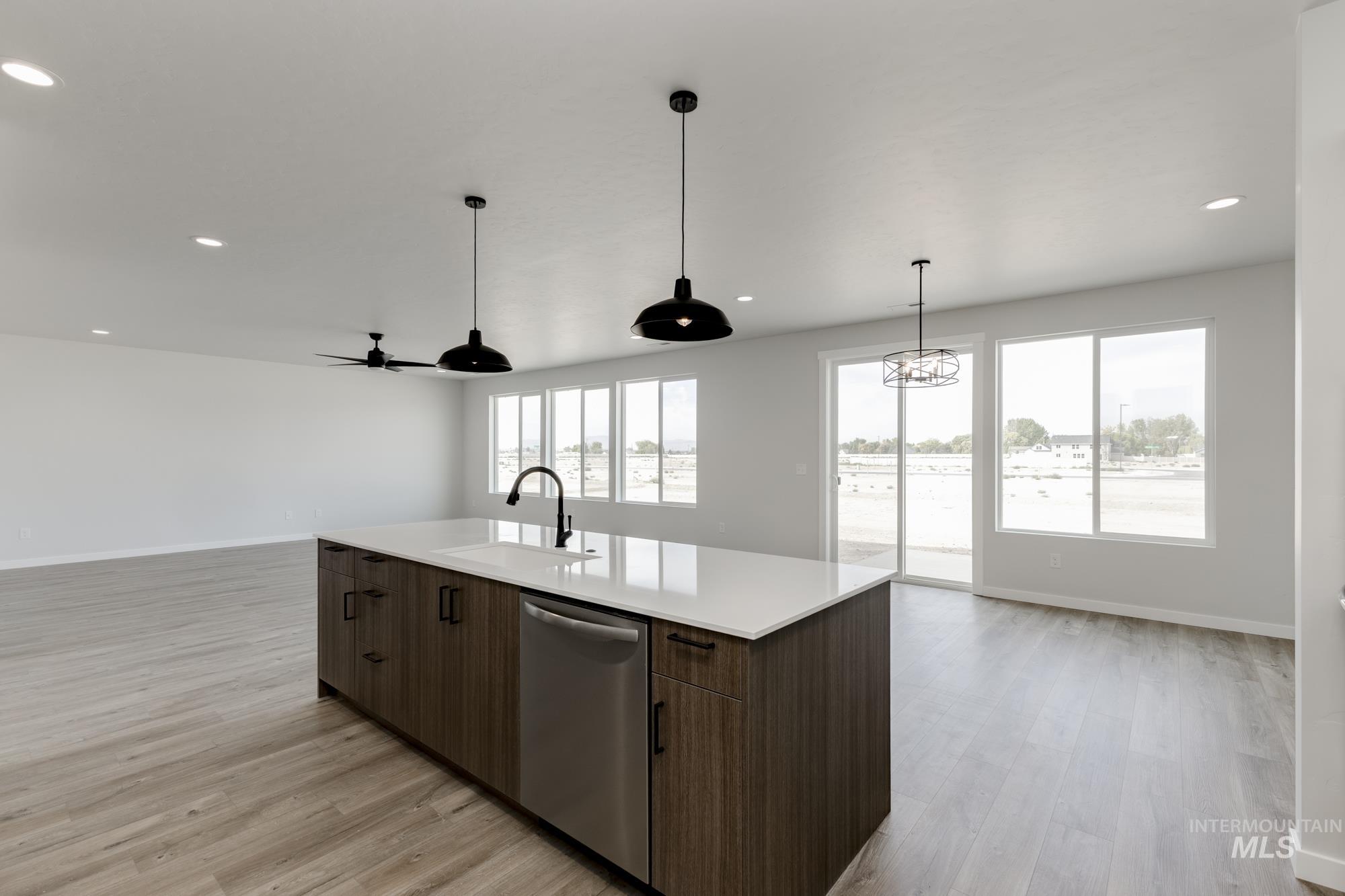 Kitchen with open floor plan, dishwasher, hanging light fixtures, light wood-type flooring, and recessed lighting