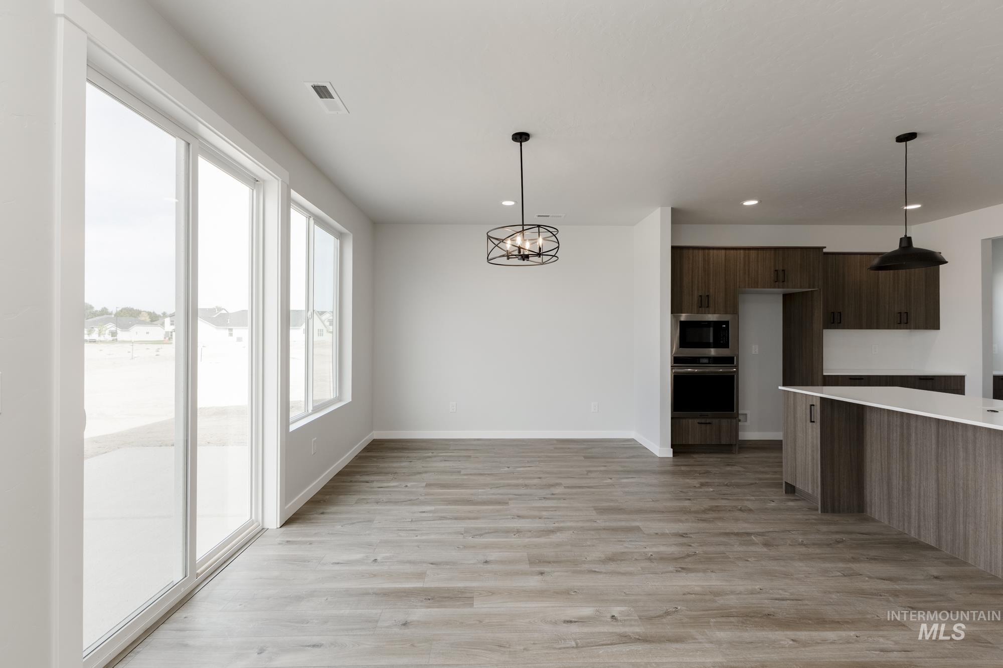 Kitchen with a chandelier, light wood-type flooring, hanging light fixtures, appliances with stainless steel finishes, and modern cabinets