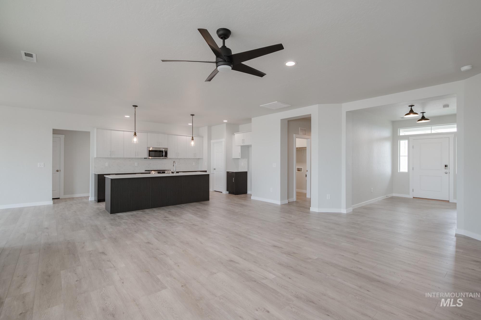 Unfurnished living room with light wood finished floors, a ceiling fan, and recessed lighting