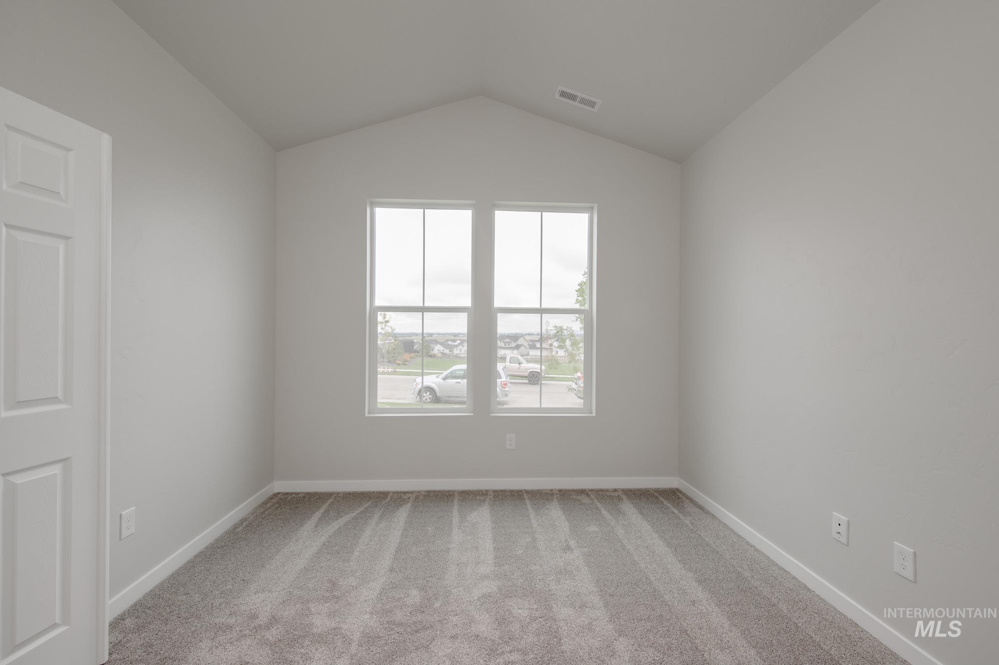 Unfurnished room with light carpet and vaulted ceiling