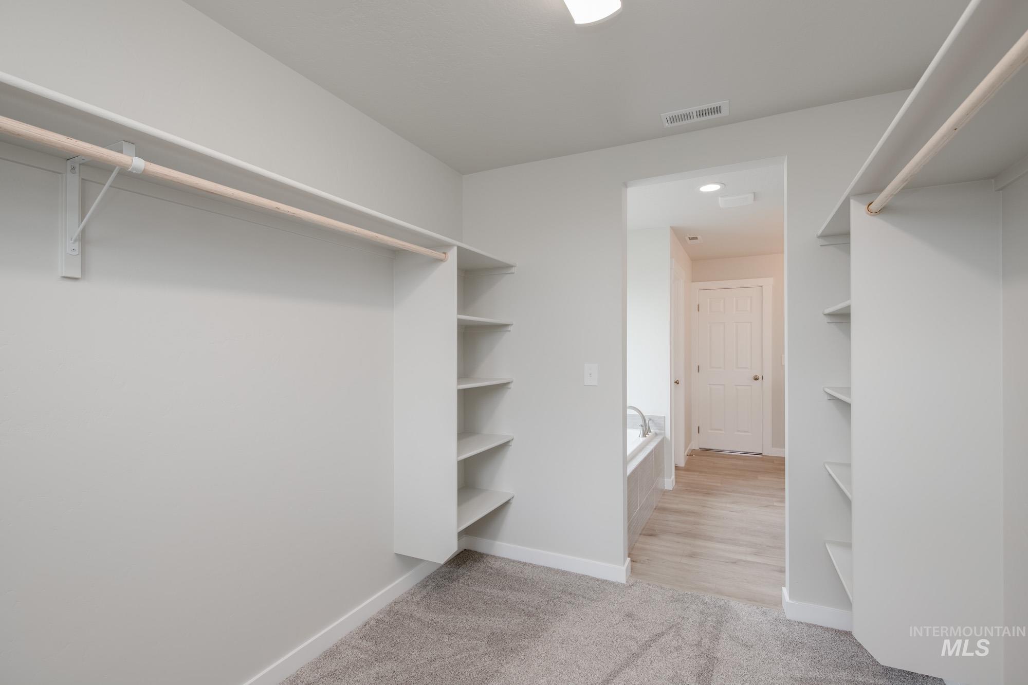 Walk in closet featuring light carpet
