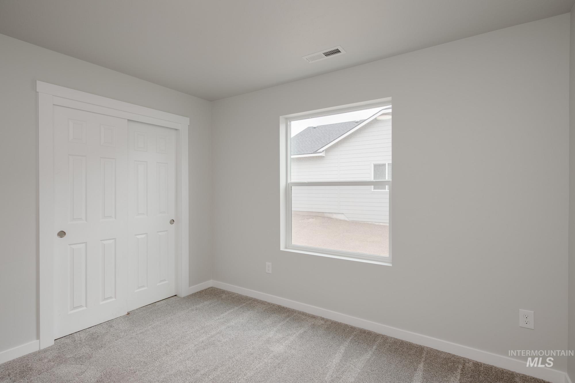 Unfurnished bedroom featuring light carpet and a closet