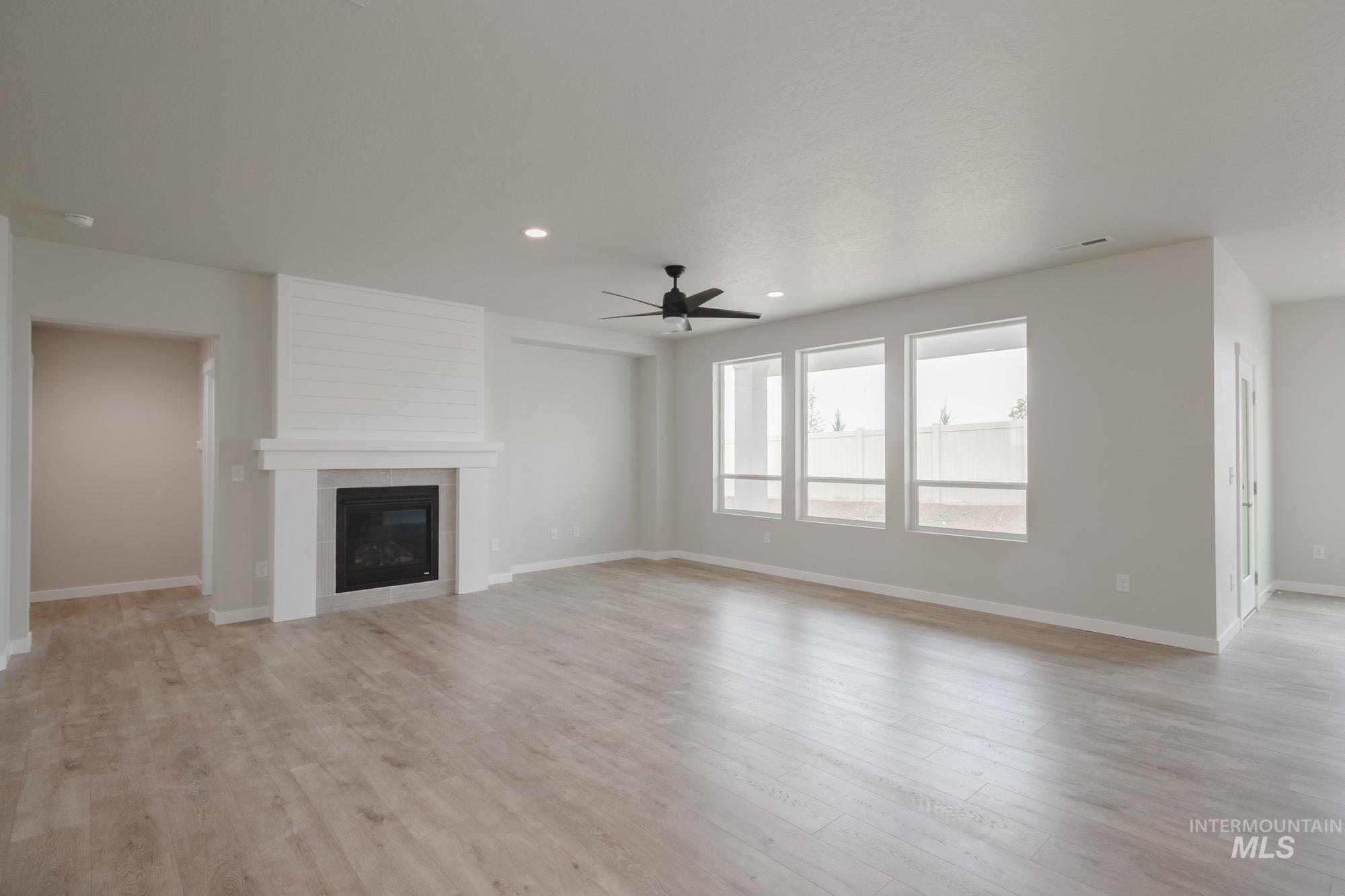 Unfurnished living room featuring ceiling fan, a tile fireplace, light wood-style flooring, and recessed lighting