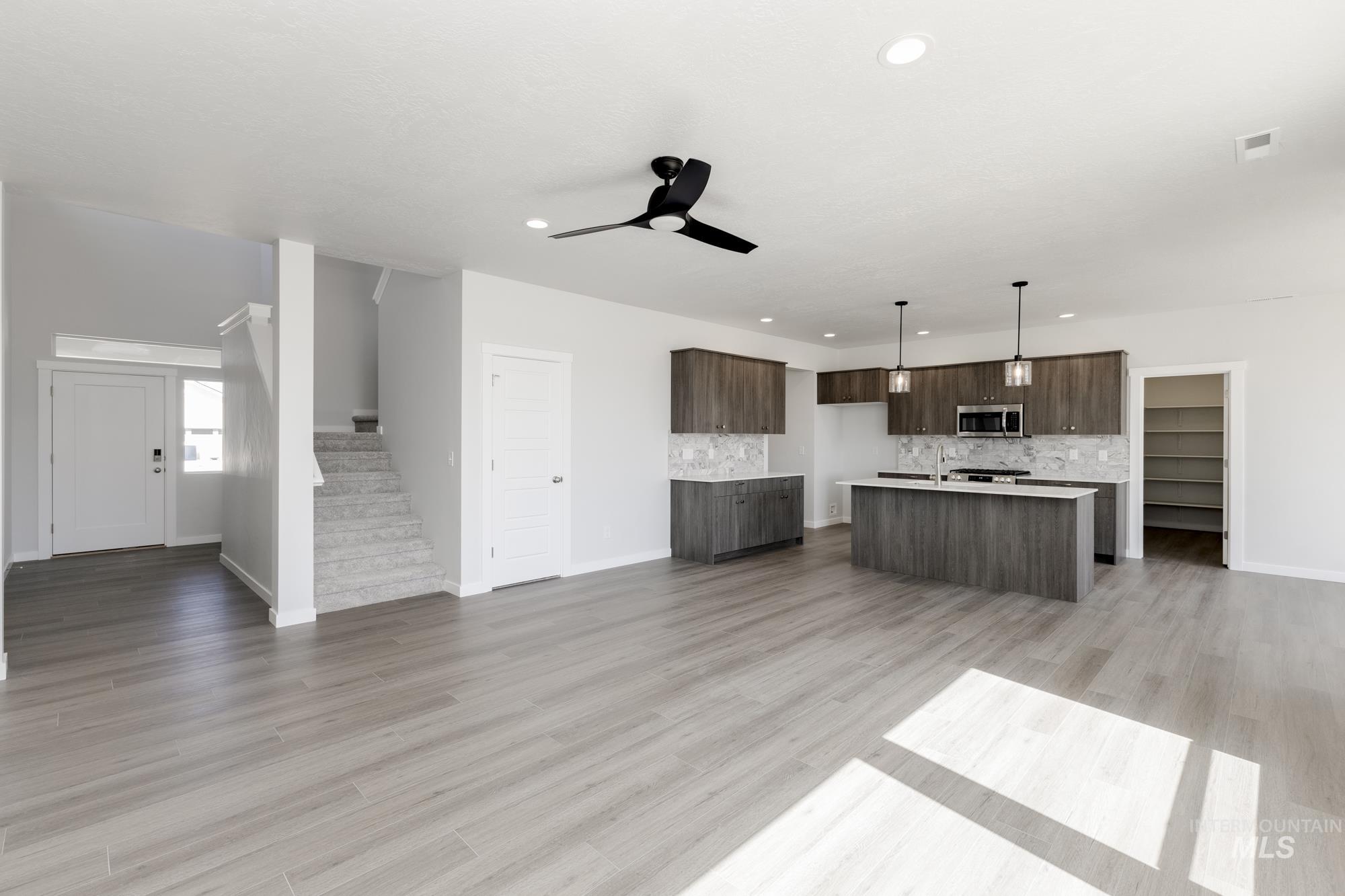 Kitchen with open floor plan, a ceiling fan, modern cabinets, an island with sink, and recessed lighting