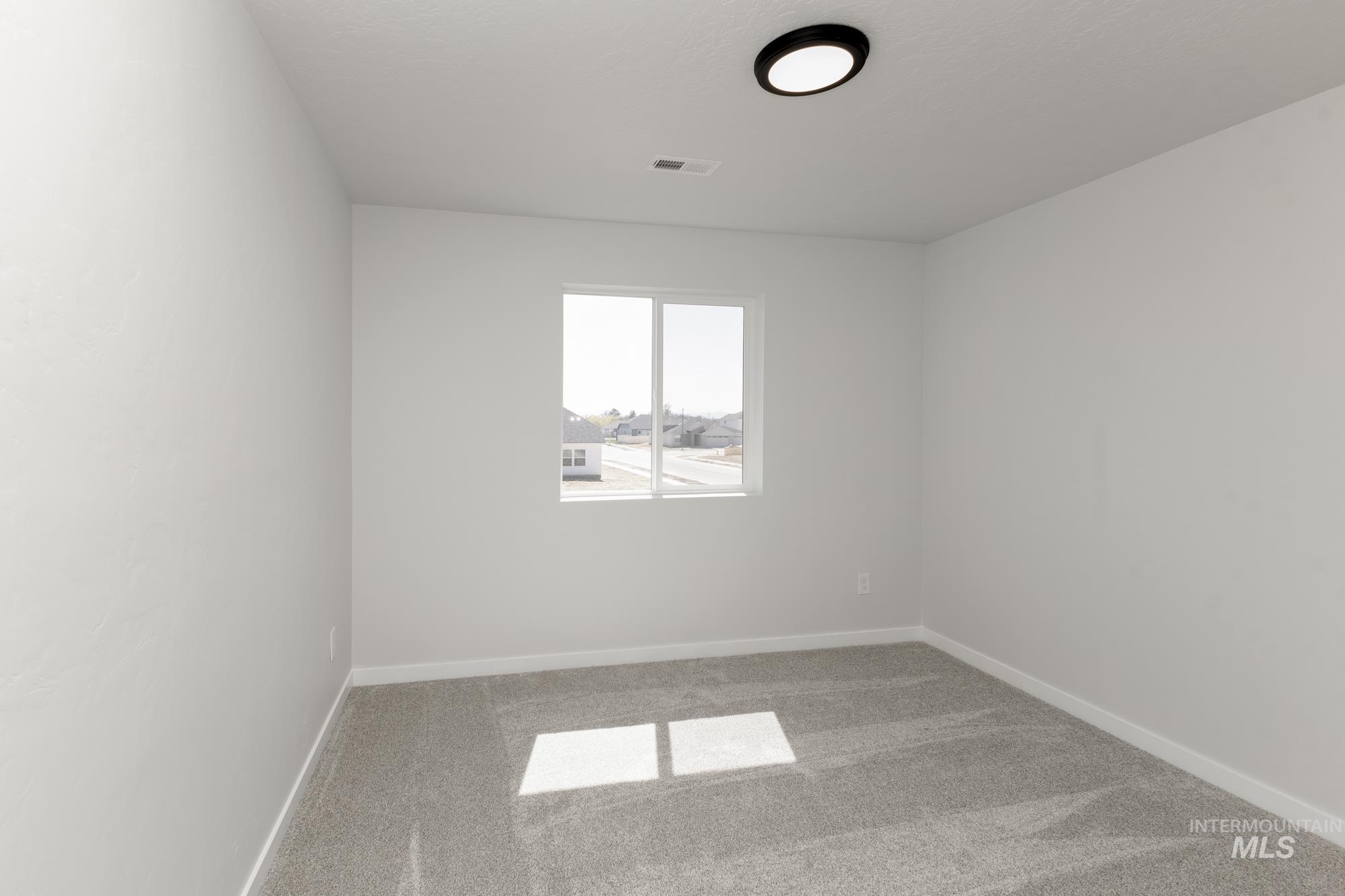 Spare room featuring light colored carpet and baseboards