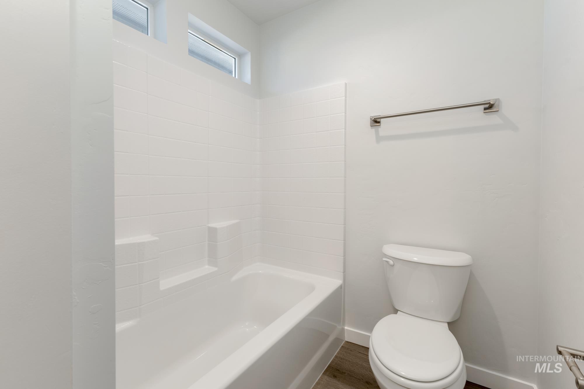 Bathroom with wood finished floors and bathing tub / shower combination