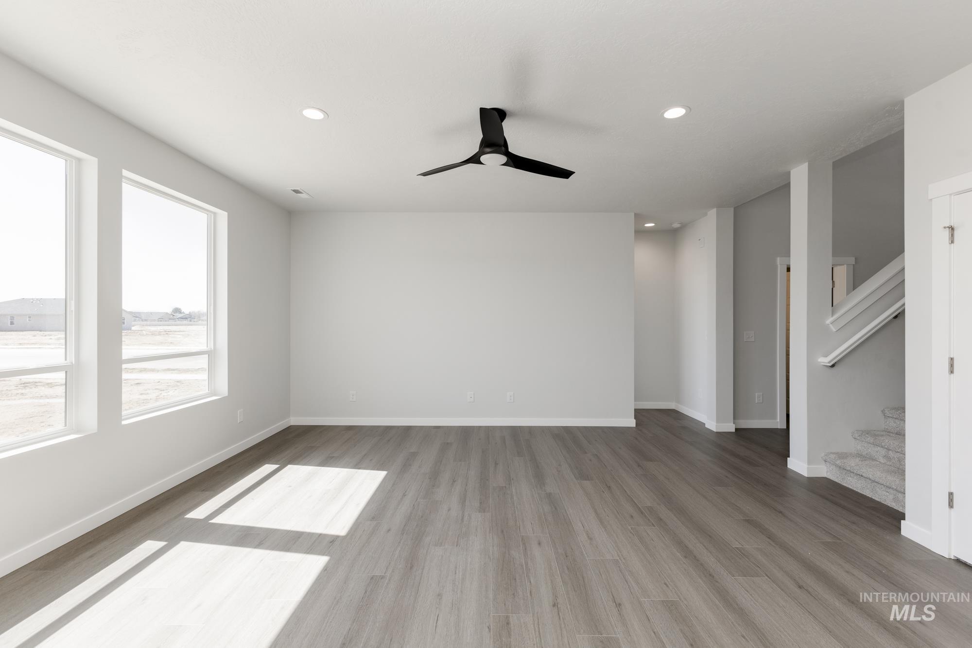 Empty room featuring stairs, recessed lighting, light wood-type flooring, and a ceiling fan