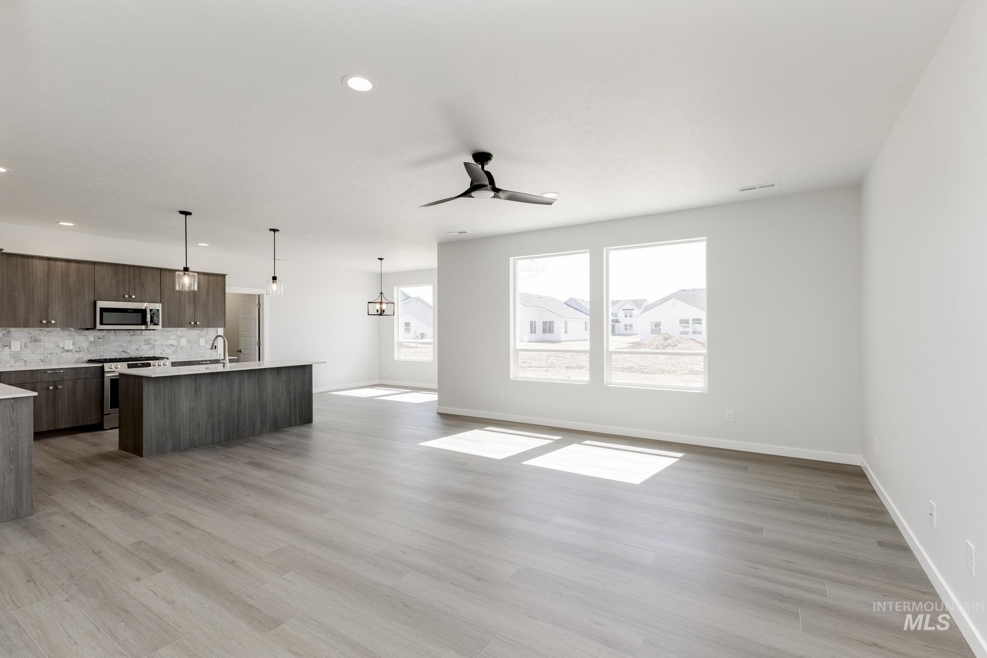 Unfurnished living room with ceiling fan, light wood-style flooring, a chandelier, and recessed lighting