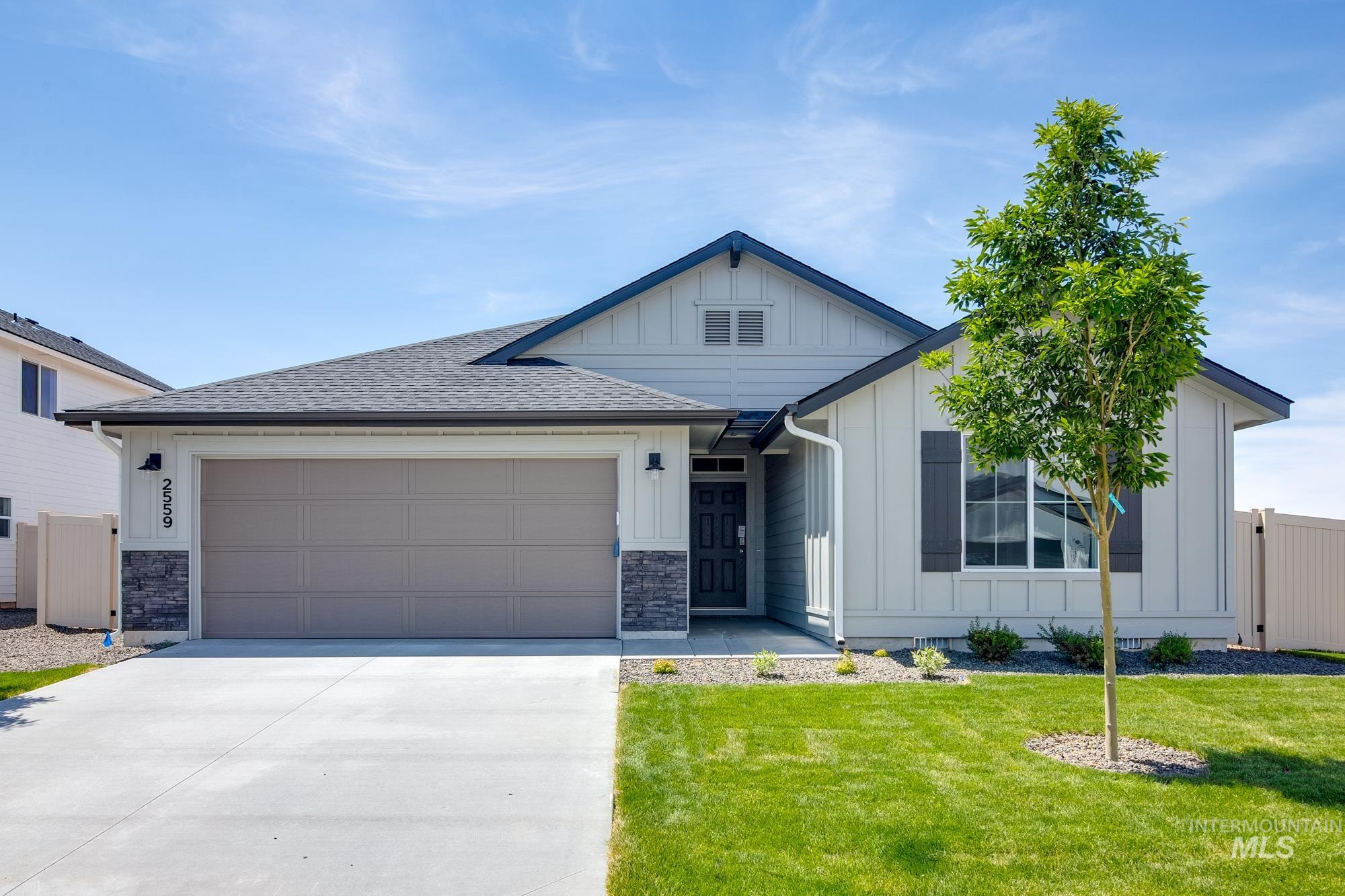 View of front facade with board and batten siding, concrete driveway, roof with shingles, an attached garage, and stone siding