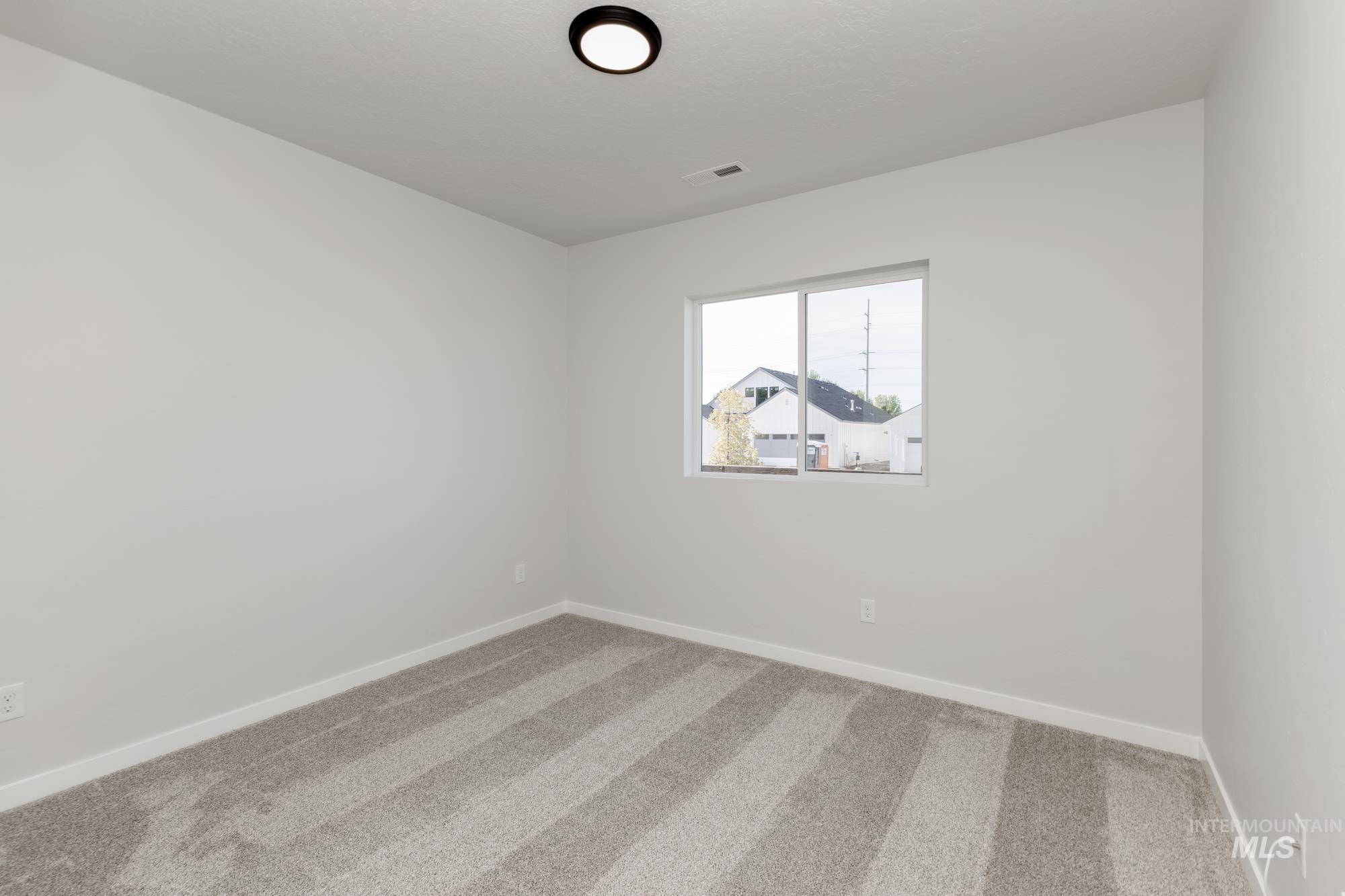 Carpeted spare room featuring baseboards