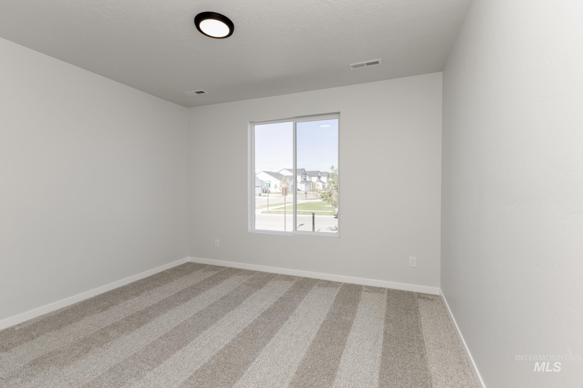 Empty room with light colored carpet and baseboards