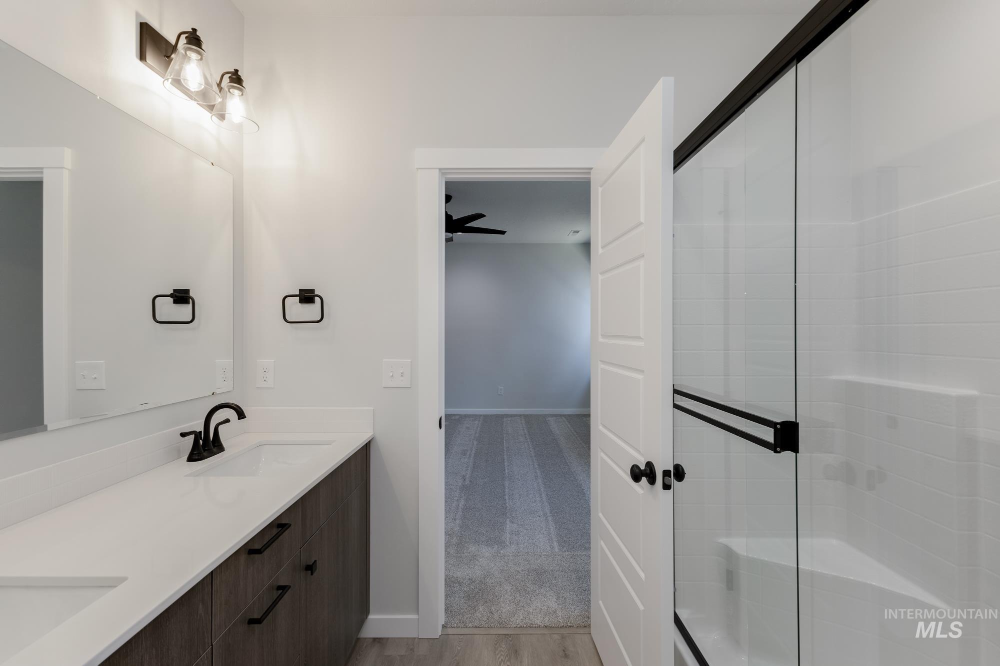 Full bathroom with double vanity, light wood-style flooring, a stall shower, and light colored carpet