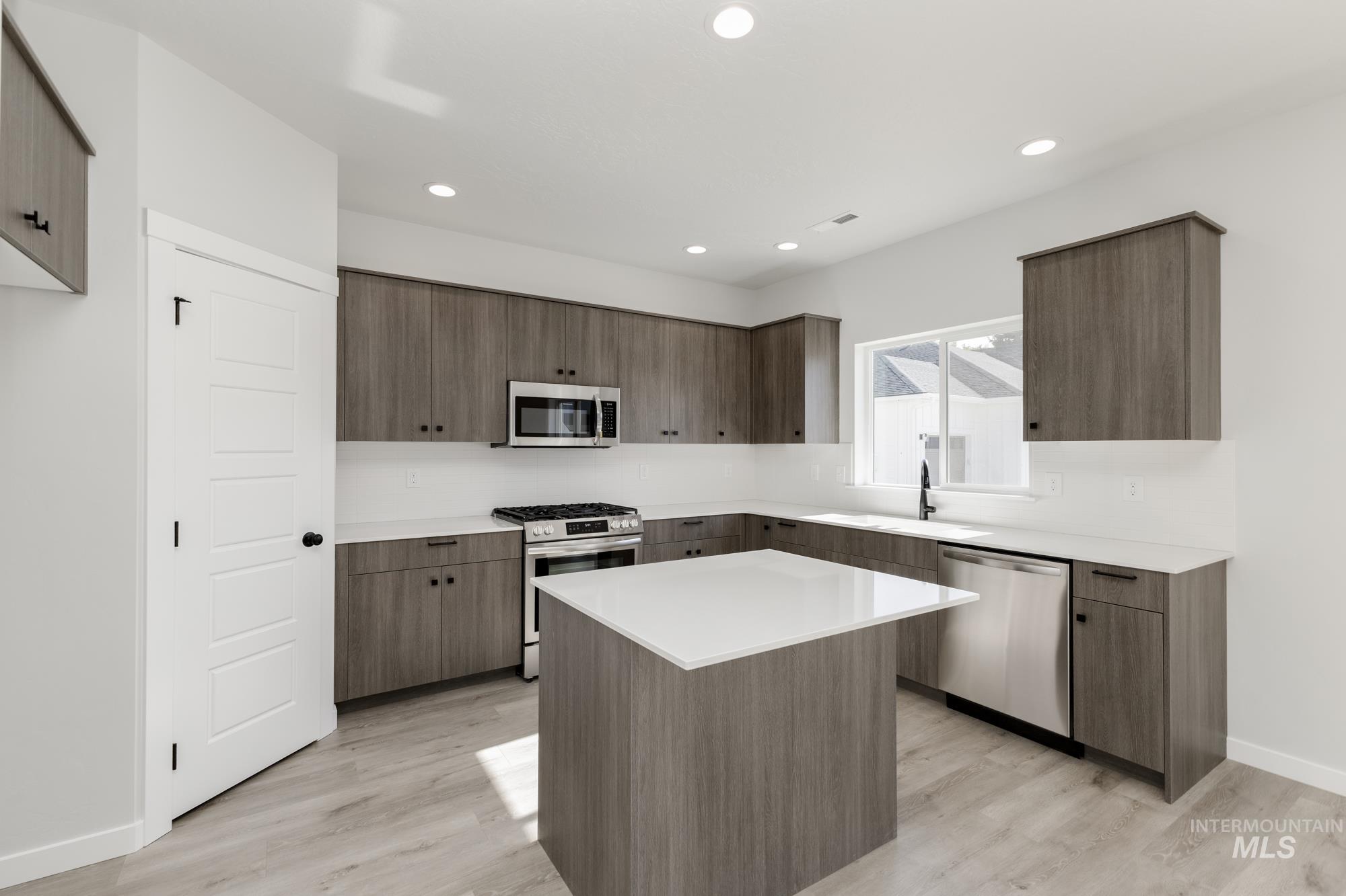 Kitchen featuring modern cabinets, stainless steel appliances, light wood-style floors, recessed lighting, and a kitchen island