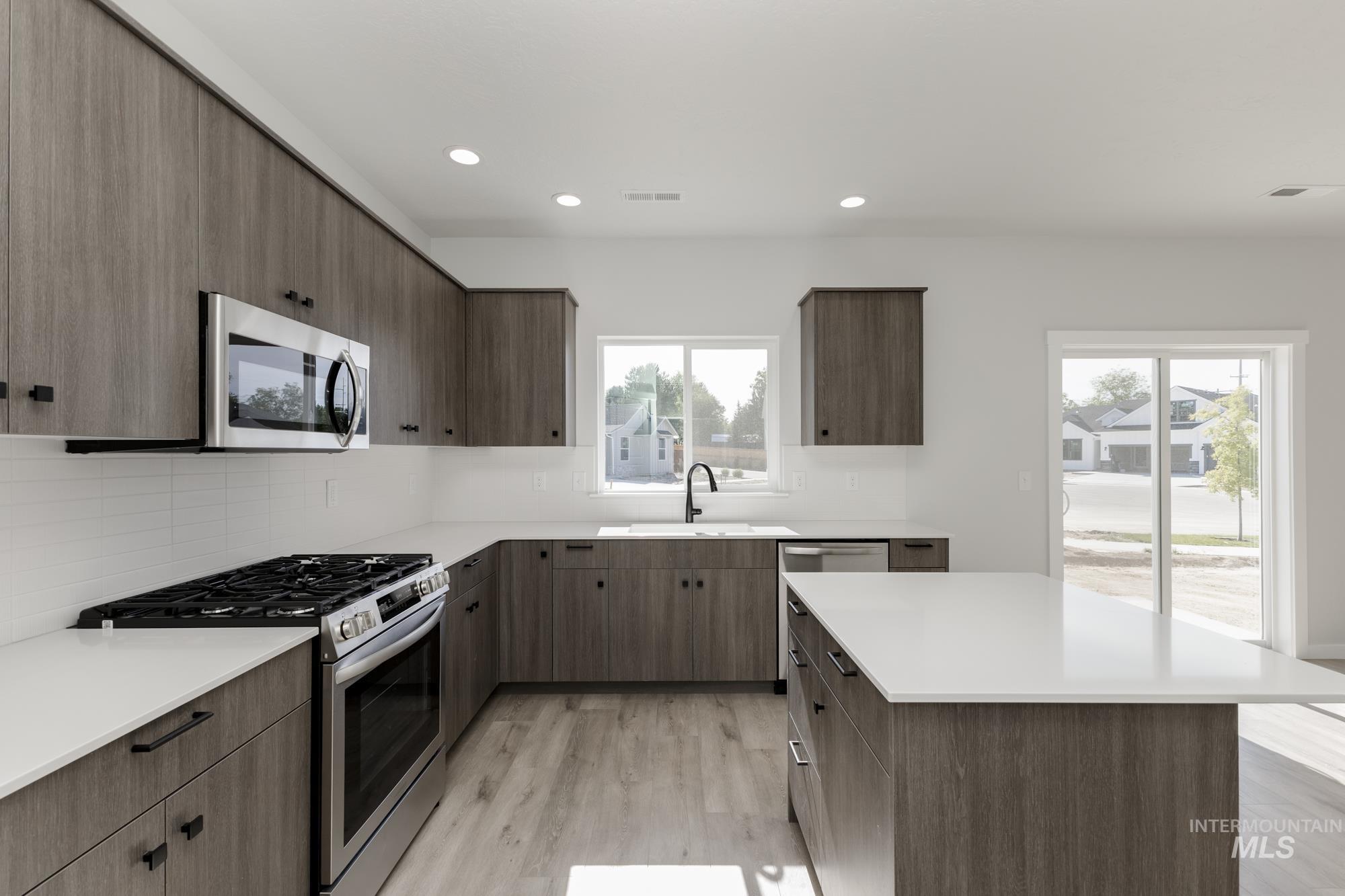 Kitchen with appliances with stainless steel finishes, tasteful backsplash, light wood-style floors, recessed lighting, and modern cabinets