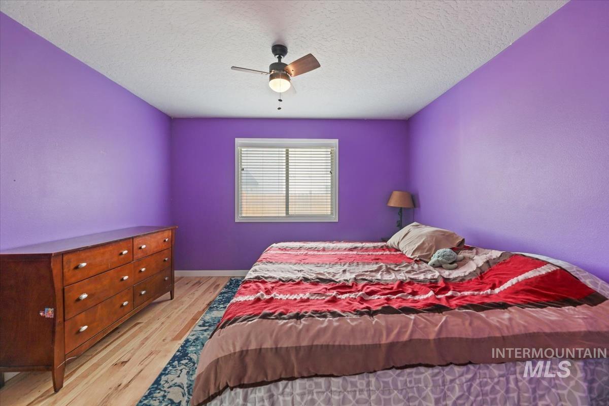 Bedroom featuring light wood-style flooring, a textured ceiling, and ceiling fan