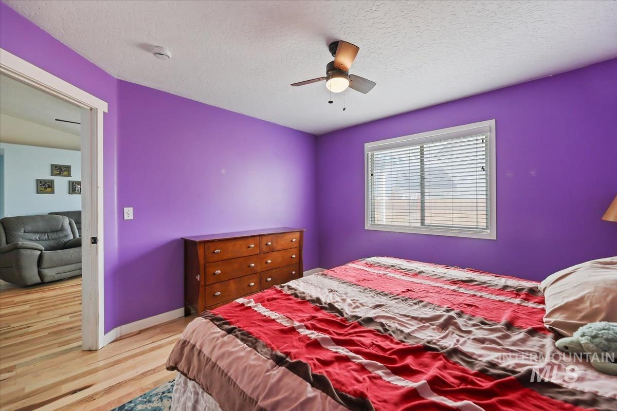 Bedroom featuring light wood-style floors, a textured ceiling, and a ceiling fan