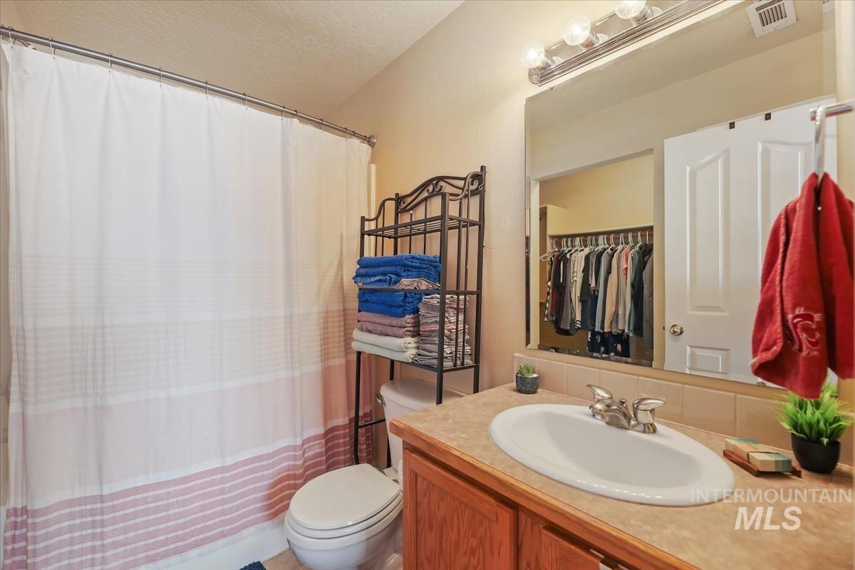 Full bath with vanity, a textured ceiling, and a spacious closet