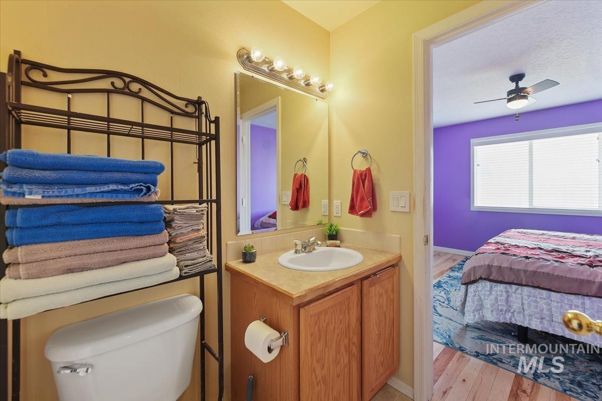 Ensuite bathroom with vanity, a ceiling fan, light wood finished floors, and a textured ceiling