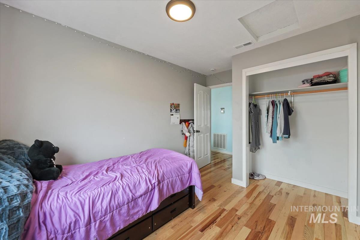 Bedroom with attic access, hardwood / wood-style flooring, and a closet