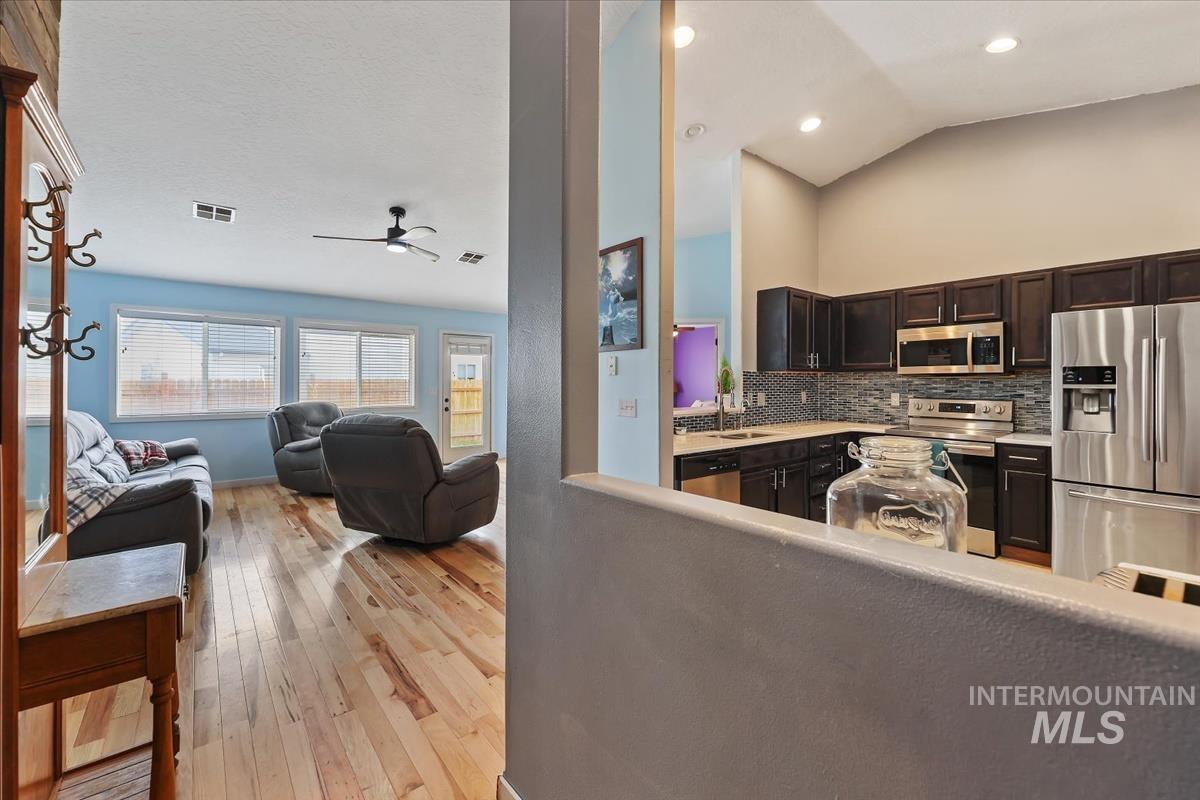 Kitchen featuring lofted ceiling, appliances with stainless steel finishes, tasteful backsplash, open floor plan, and light wood-style flooring