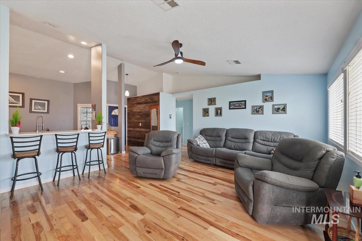Living room featuring light wood finished floors, ceiling fan, lofted ceiling, and recessed lighting