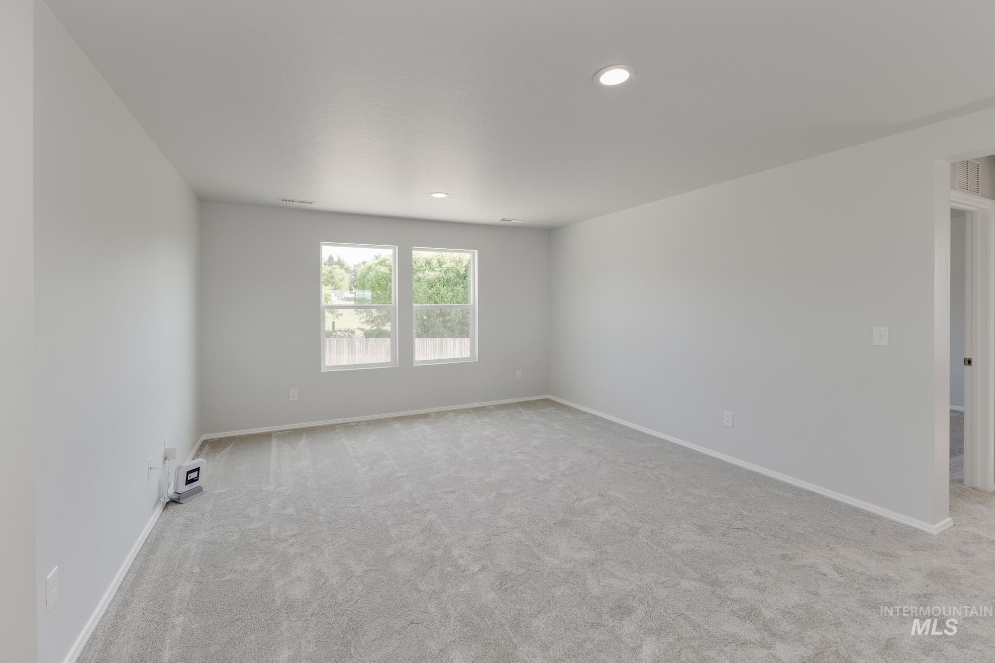 Empty room with light colored carpet and recessed lighting