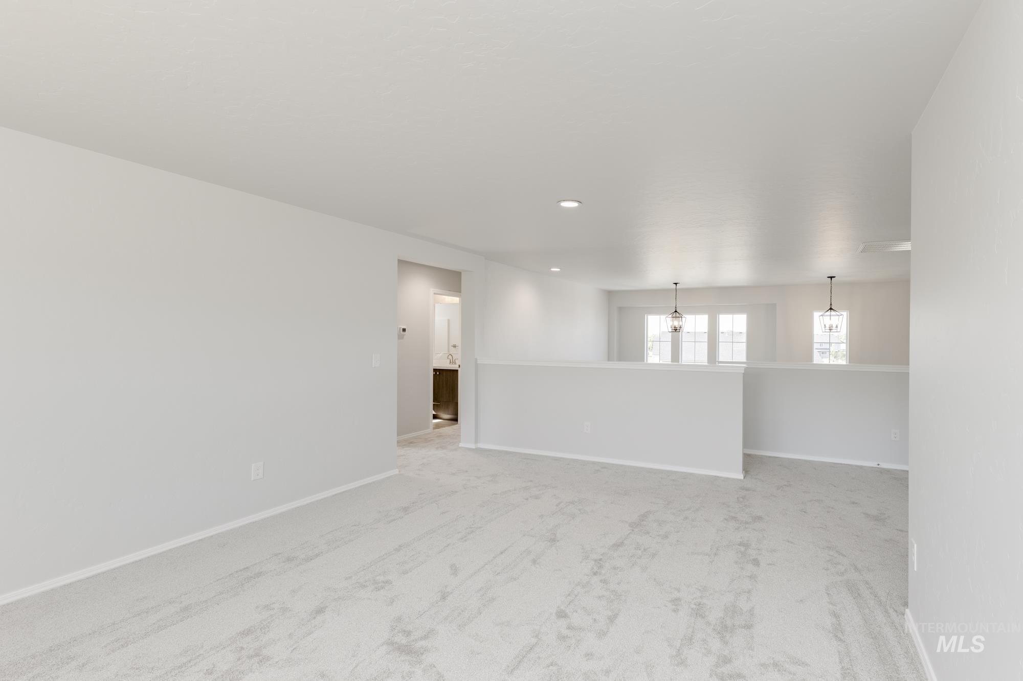 Empty room featuring light carpet, recessed lighting, and a chandelier