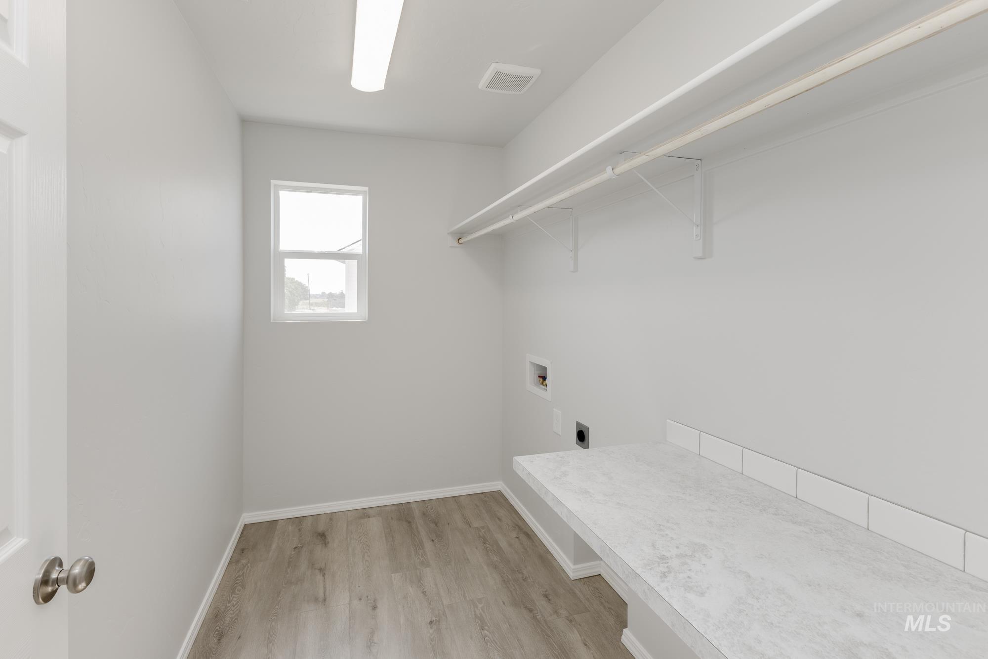 Laundry area featuring light wood-style floors, hookup for a washing machine, and electric dryer hookup