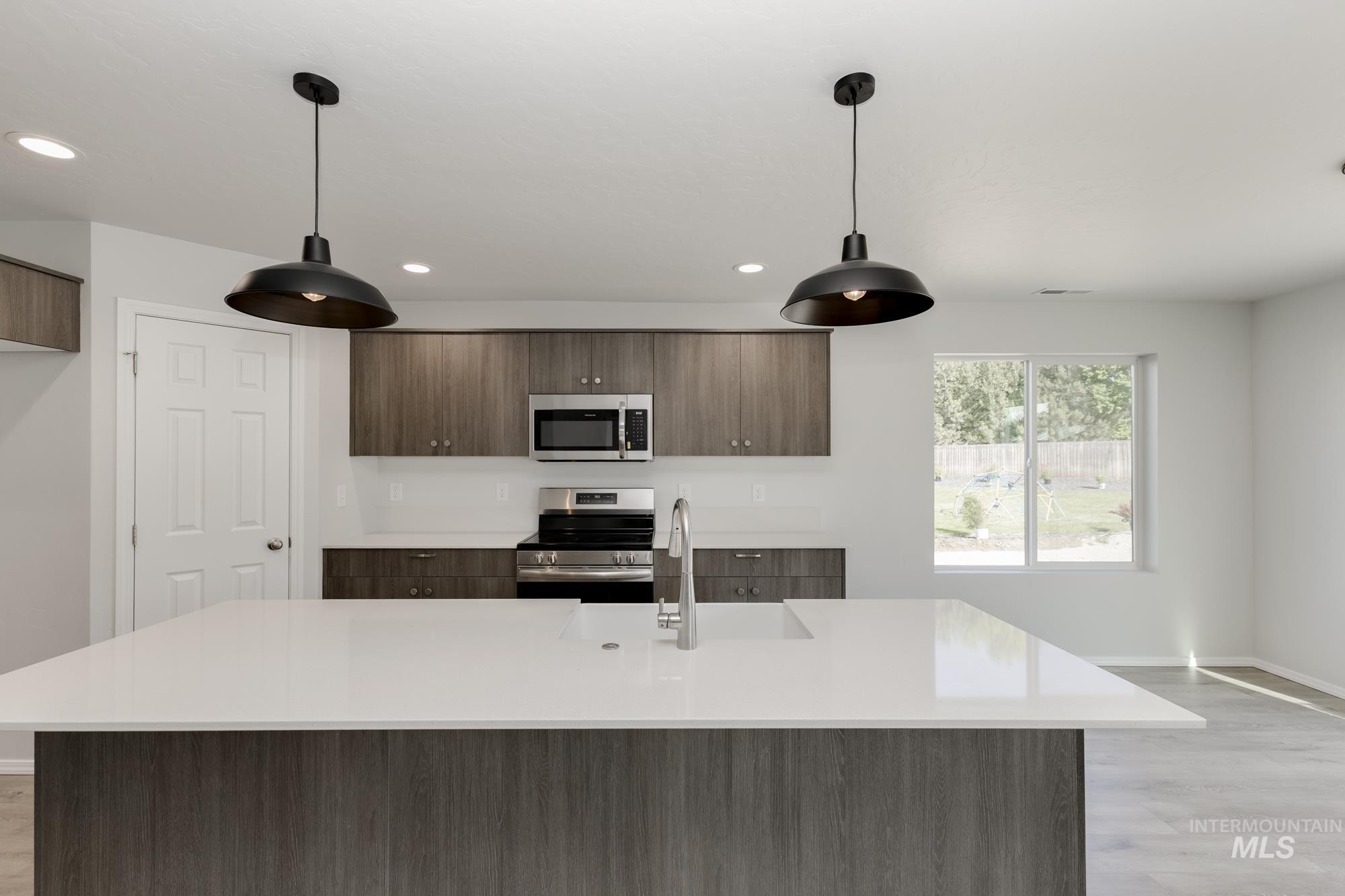 Kitchen featuring light wood-style floors, modern cabinets, appliances with stainless steel finishes, a kitchen island with sink, and recessed lighting