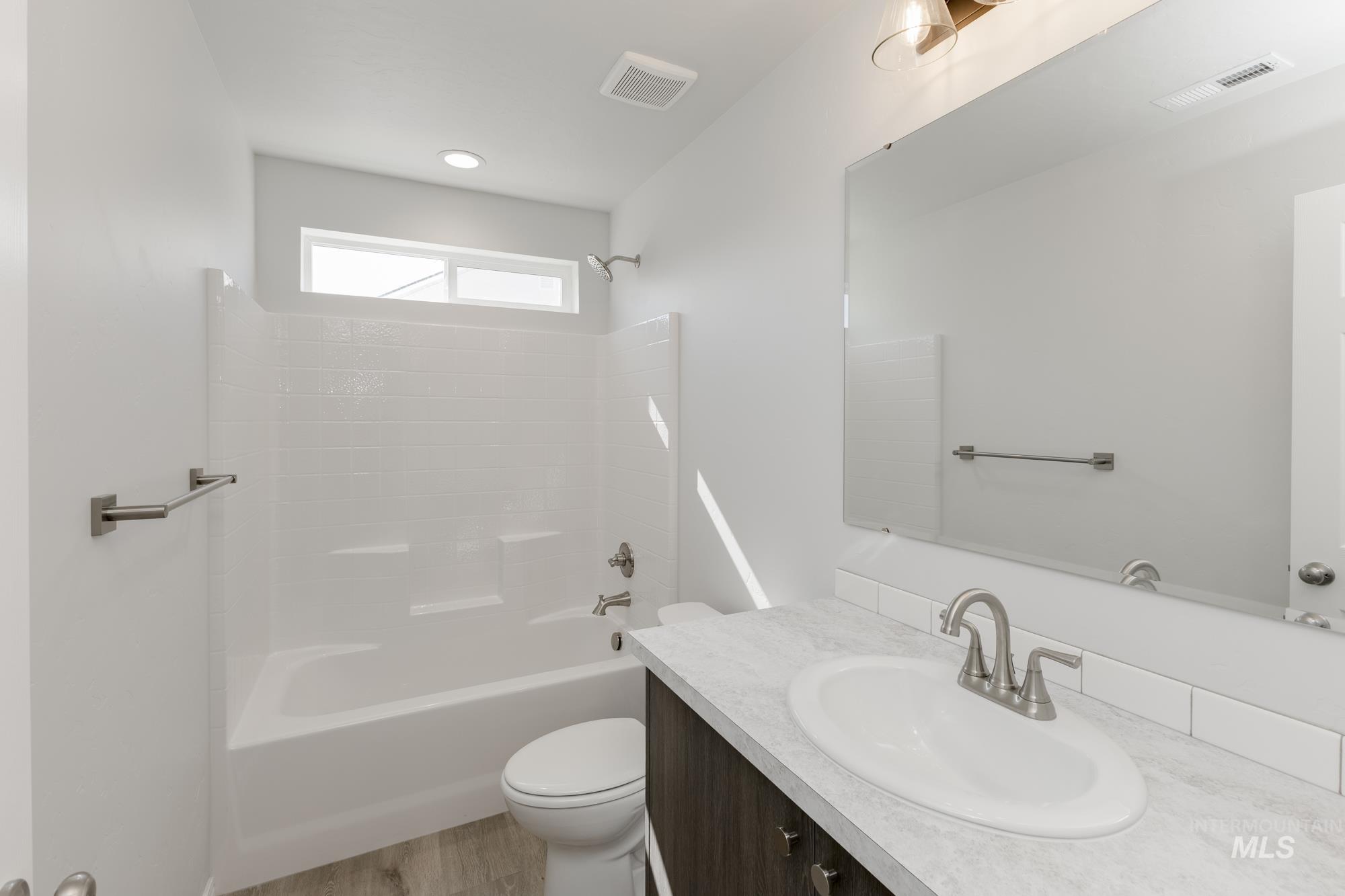 Bathroom featuring bathing tub / shower combination, vanity, and light wood finished floors