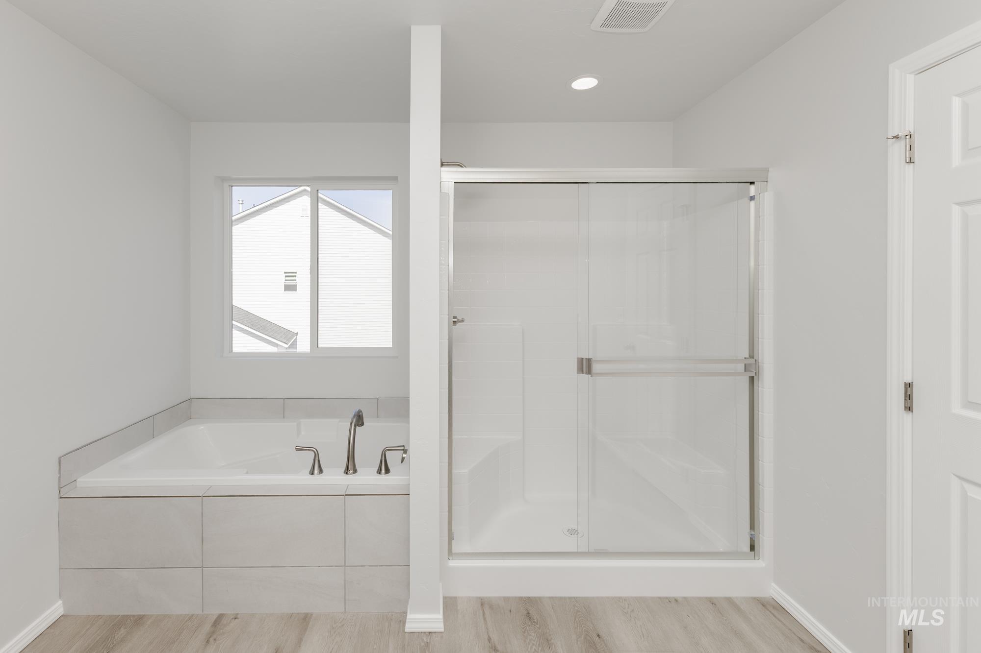 Full bath with a garden tub, a shower stall, light wood finished floors, and recessed lighting