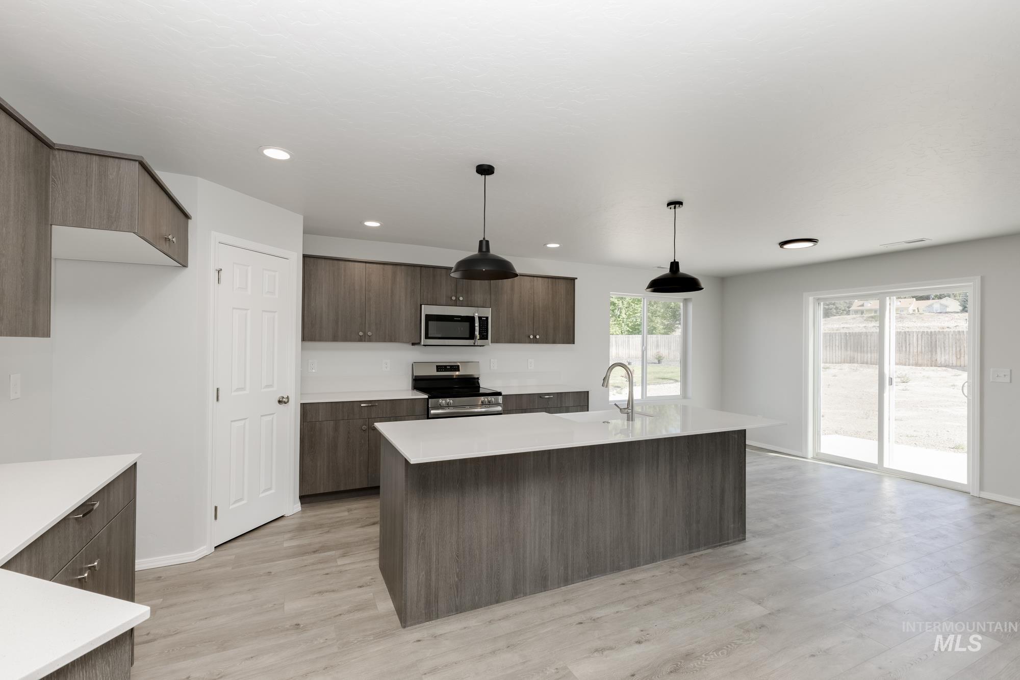 Kitchen featuring stainless steel appliances, modern cabinets, light wood-type flooring, a center island with sink, and recessed lighting