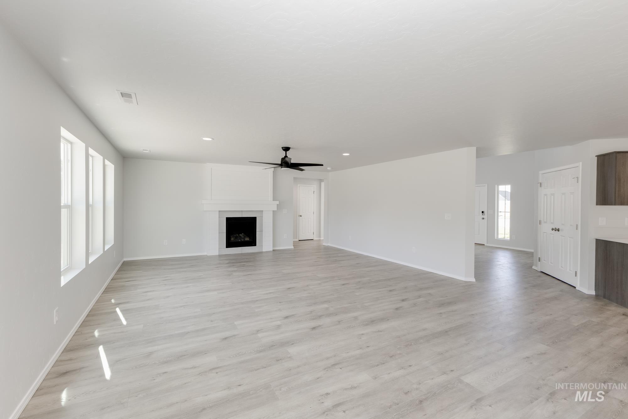 Unfurnished living room with plenty of natural light, light wood-style flooring, a fireplace, and recessed lighting