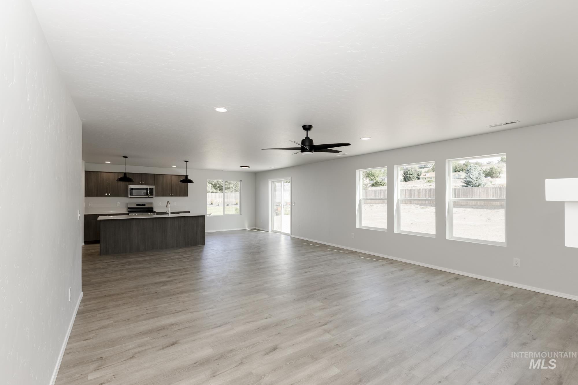 Unfurnished living room featuring light wood-style flooring, a ceiling fan, and recessed lighting